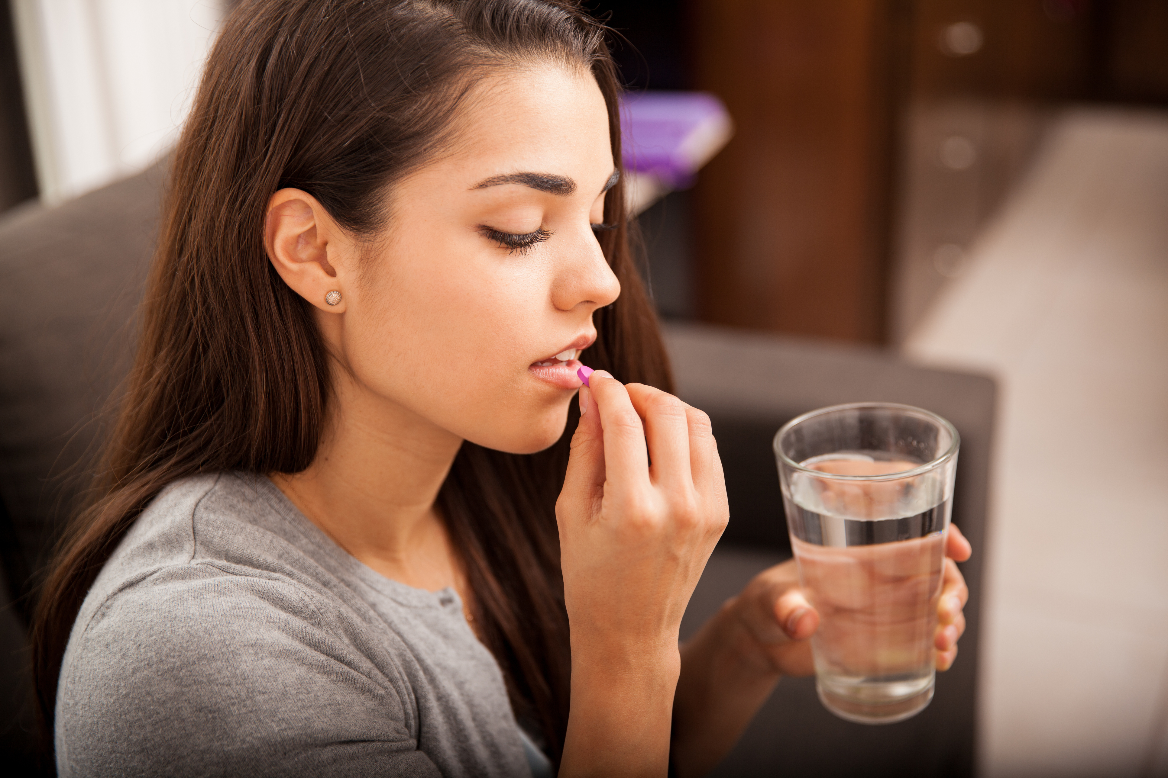 Generic photo of a young woman taking a pill