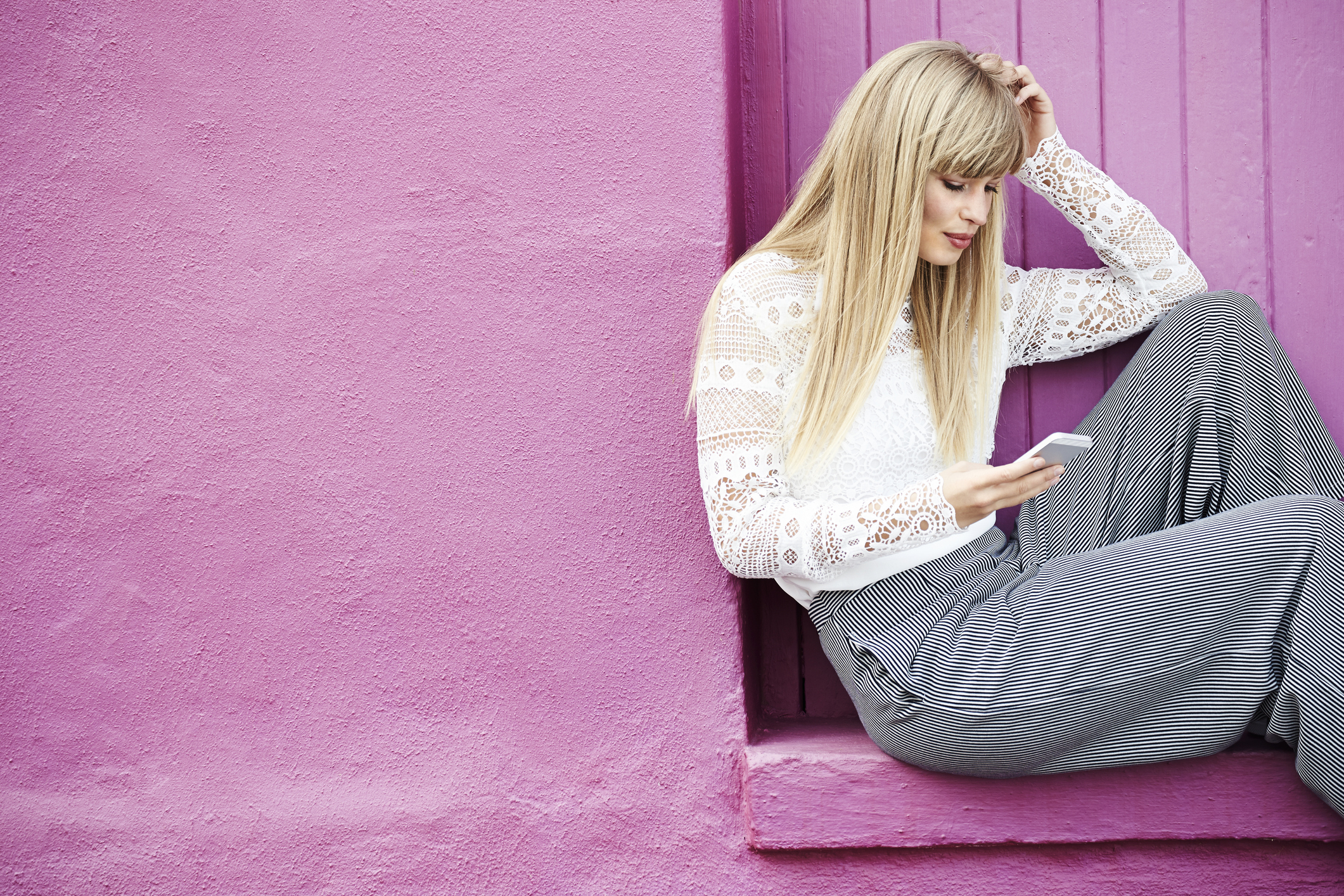 A young woman using her phone against pink wall (Thinkstock/PA)