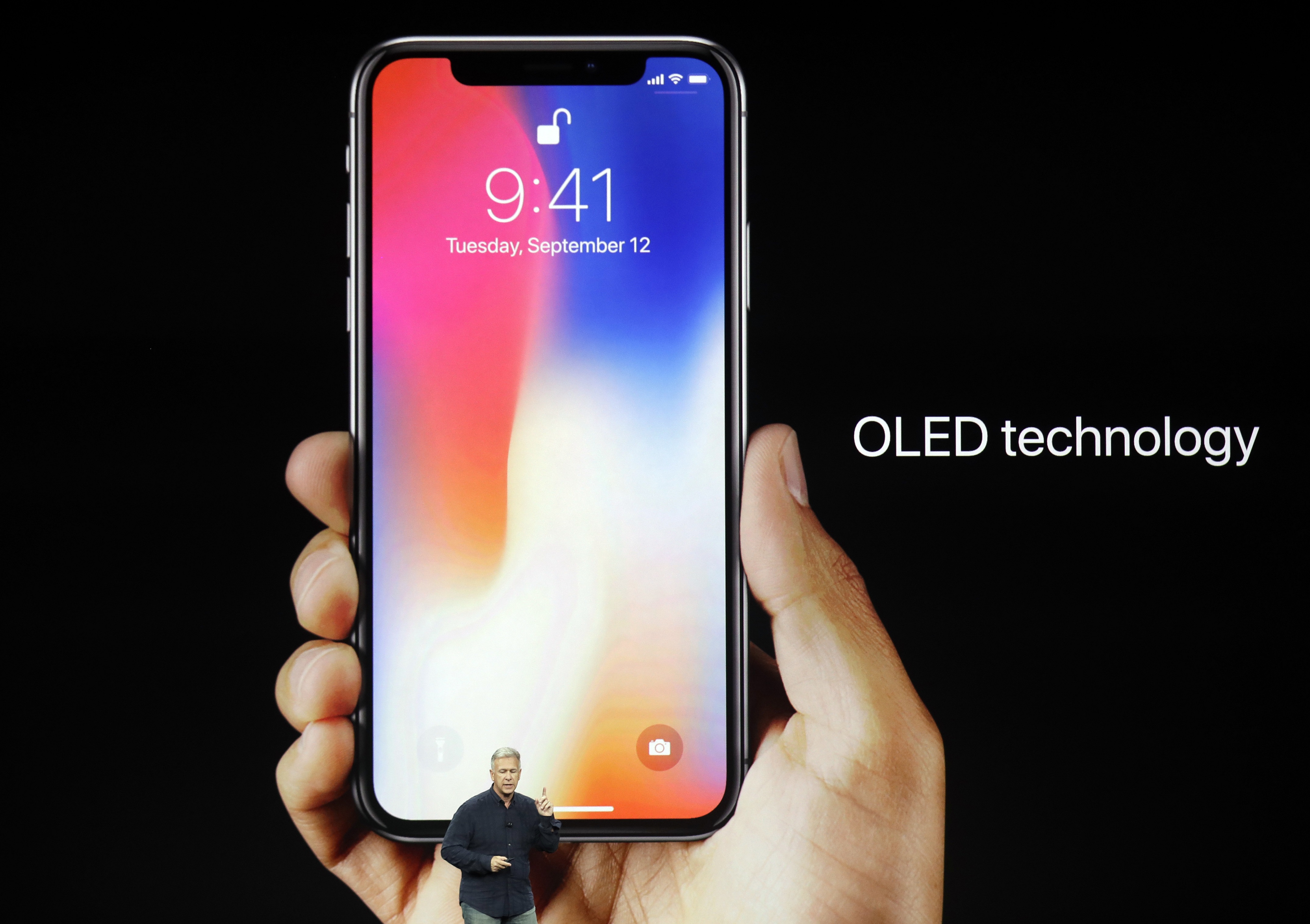 The iPhone X in someone's hand behind Schiller