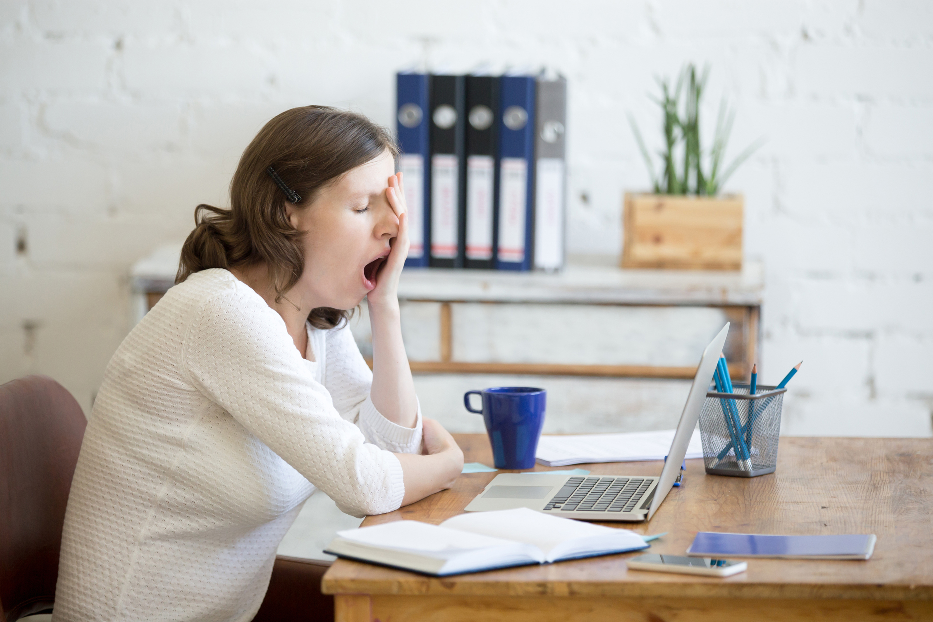 A woman yawning at her desk (Thinkstock/PA)