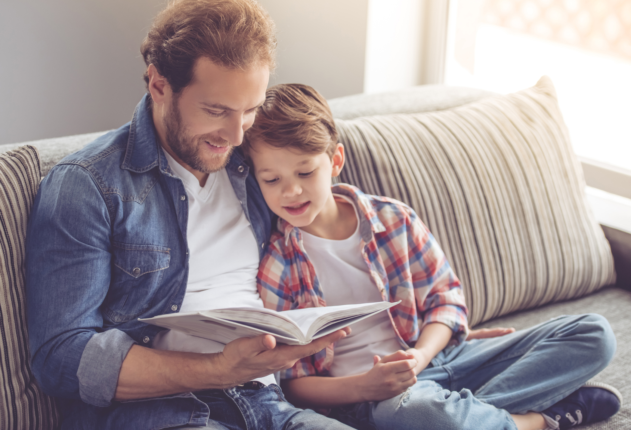 Father and son are reading a book and smiling while spending time together at home (Thinkstock/PA)