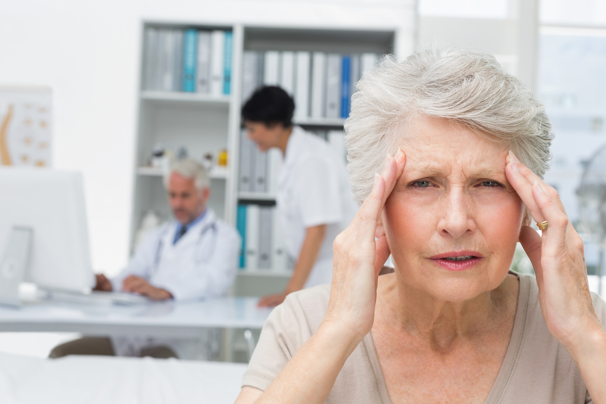 A woman holds her hands to her head, with doctors behind her (Thinkstock/PA)