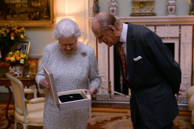 The Queen, with the Duke of Edinburgh, examining a gift (PA)