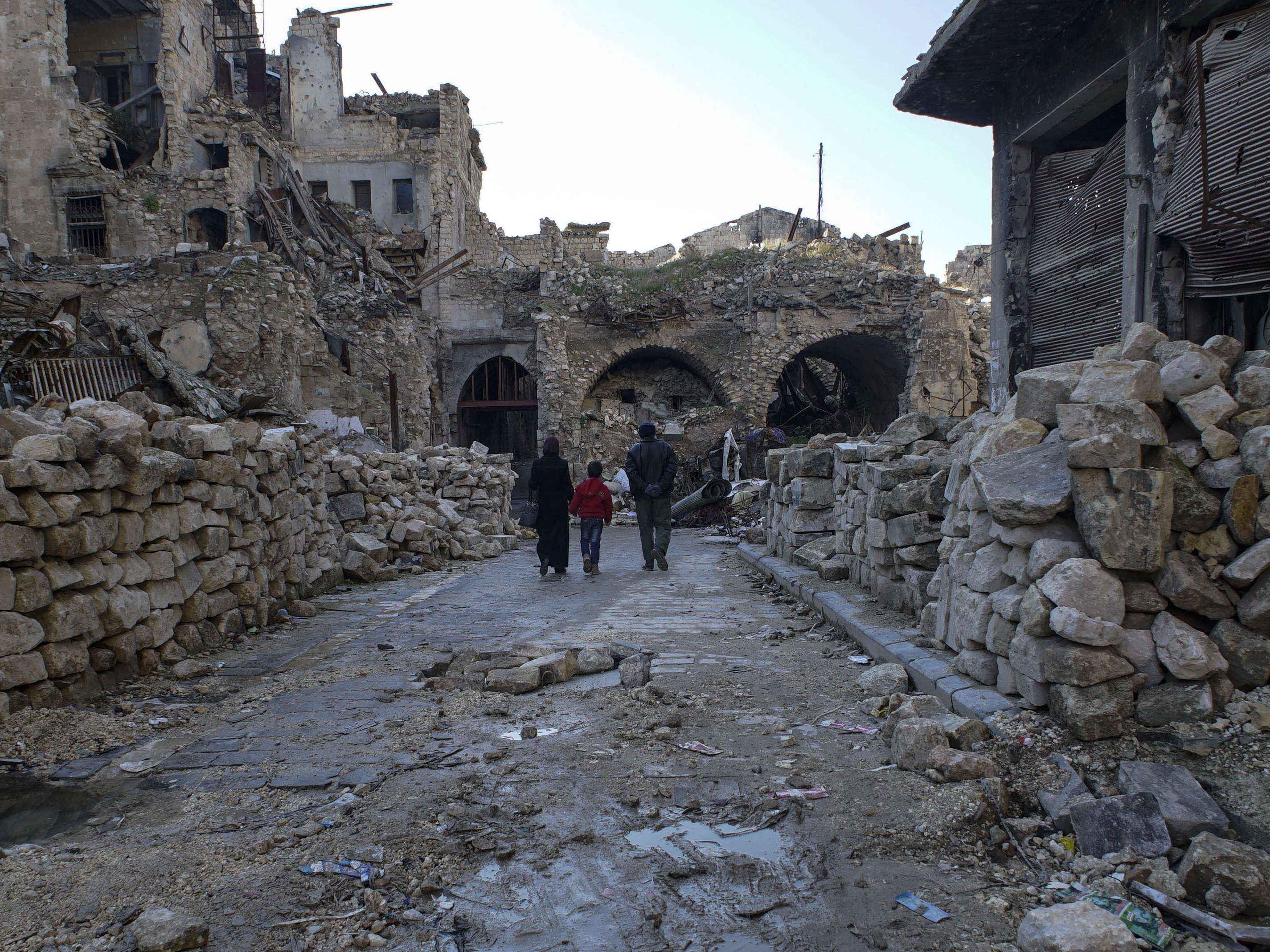 A Syrian family walks through Aleppo's devastated old market (Mstyslav Chernov/AP)