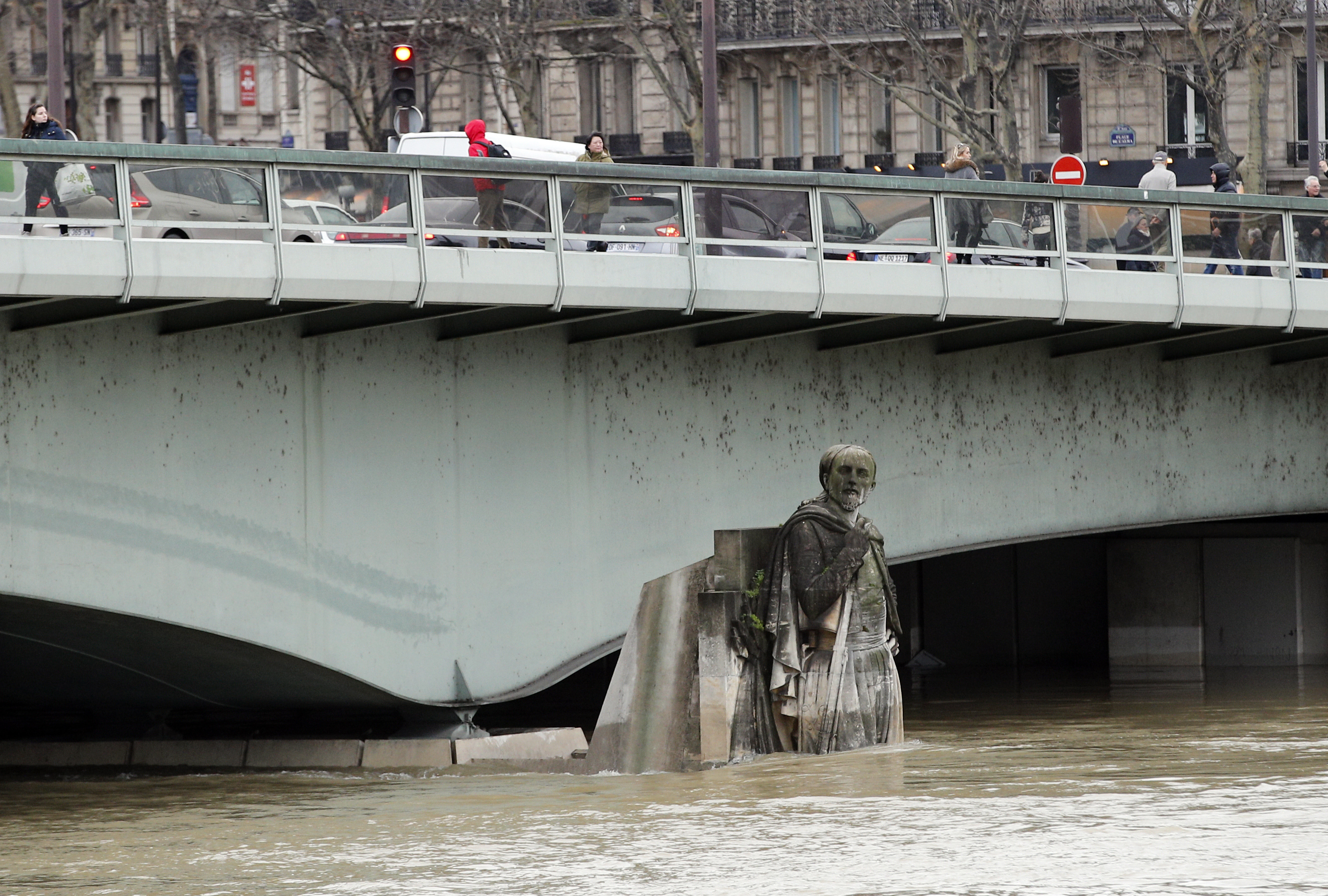 People walk on the Alma bridge by the Zouave statue which is used as a measuring instrument during floods in Paris (Christophe Ena/AP)