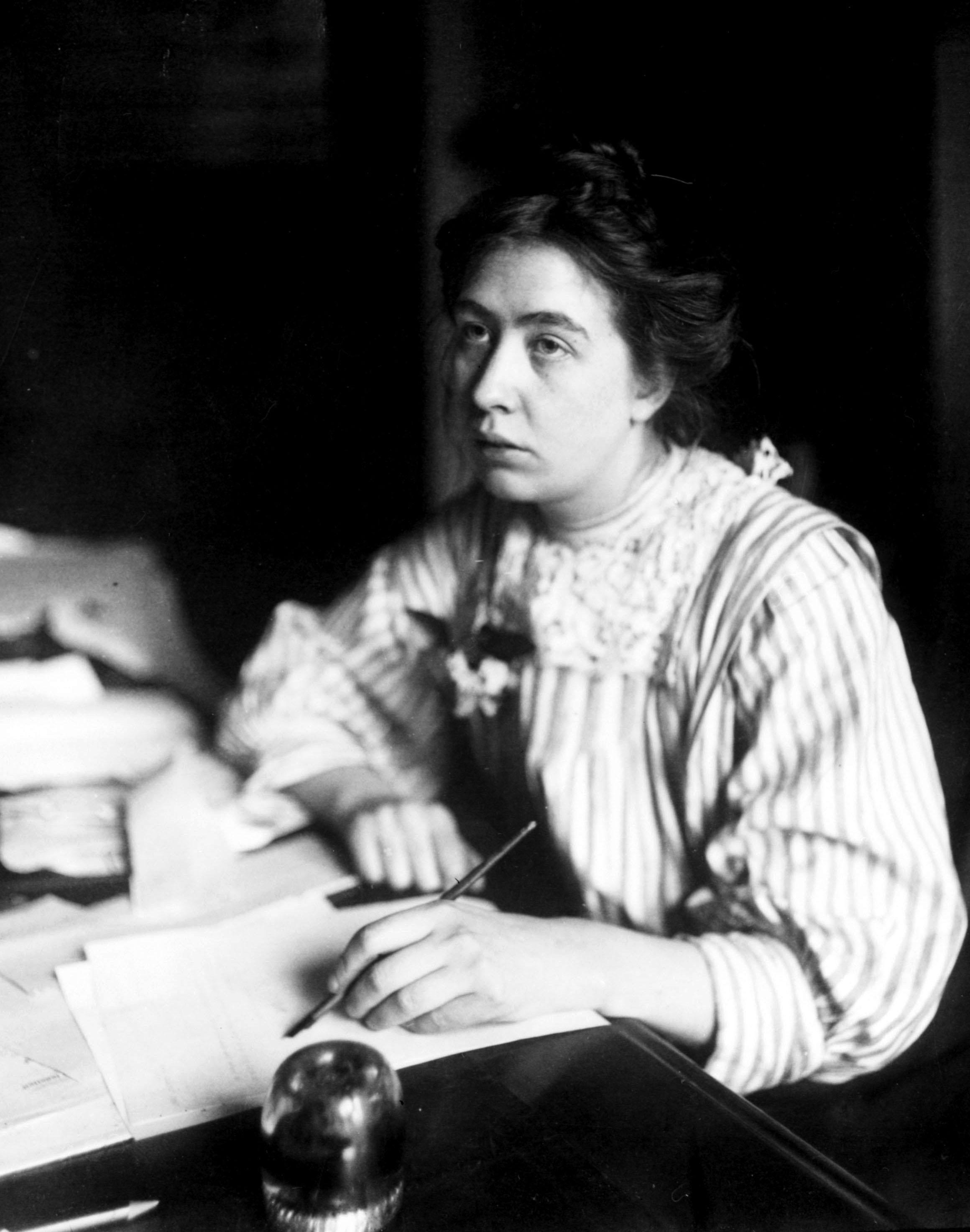 Woman in Edwardian clothing writing at her desk