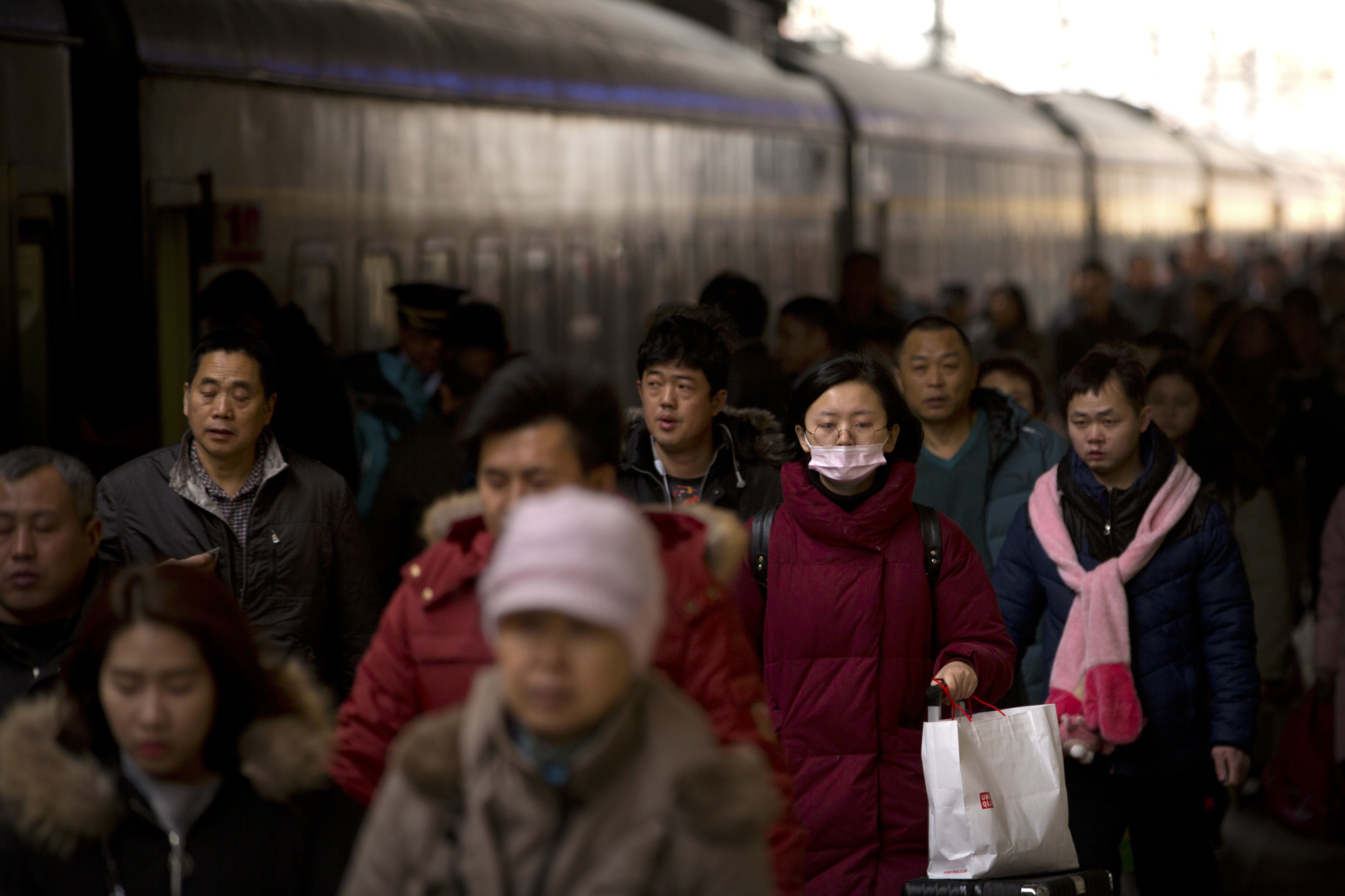 People walk to board a train at the Beijing Railway Station (Mark Schiefelbein/AP)