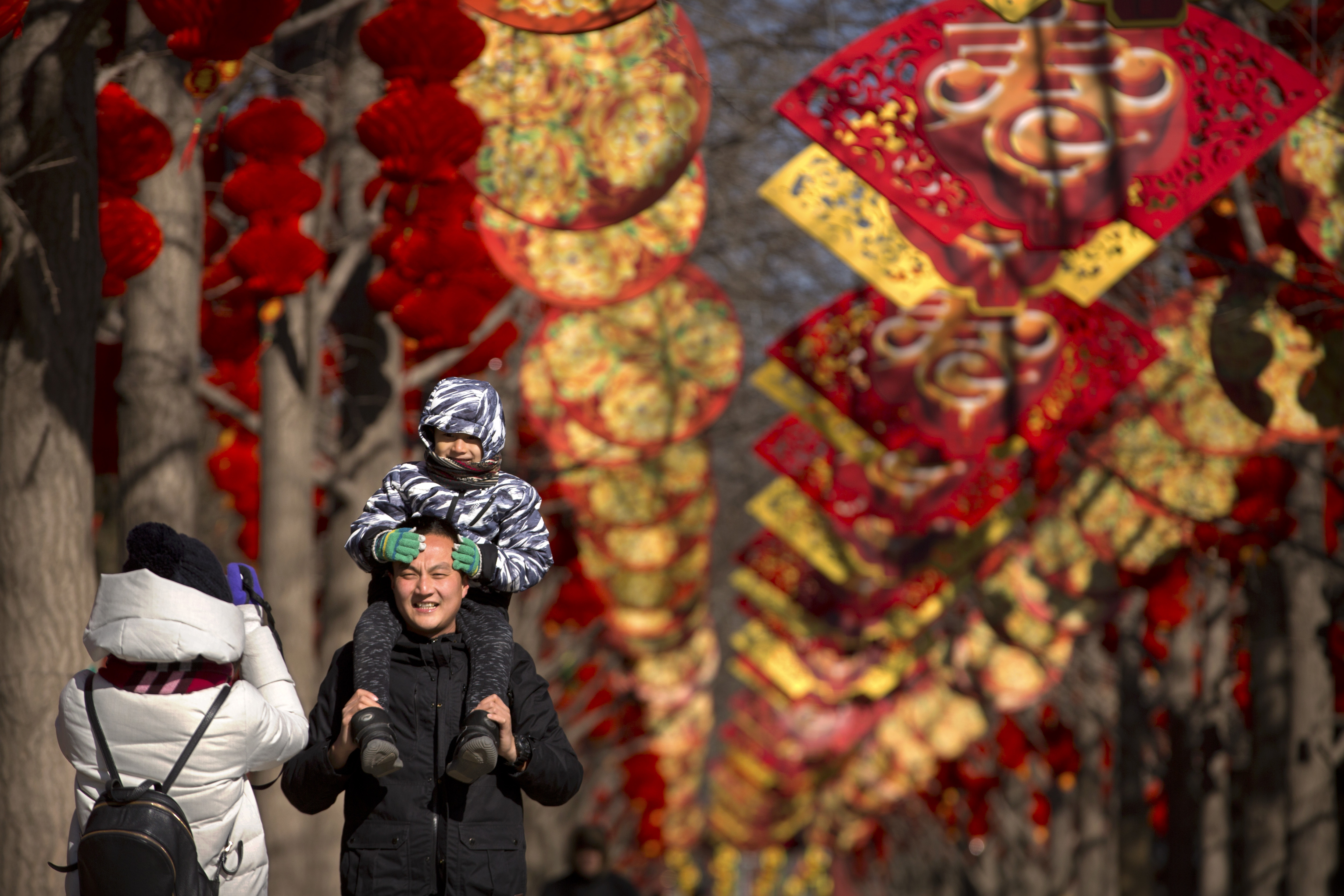 A man holds a child as they pose for a photo near a pathway decorated for the Lunar New Year (Mark Schiefelbein/AP)