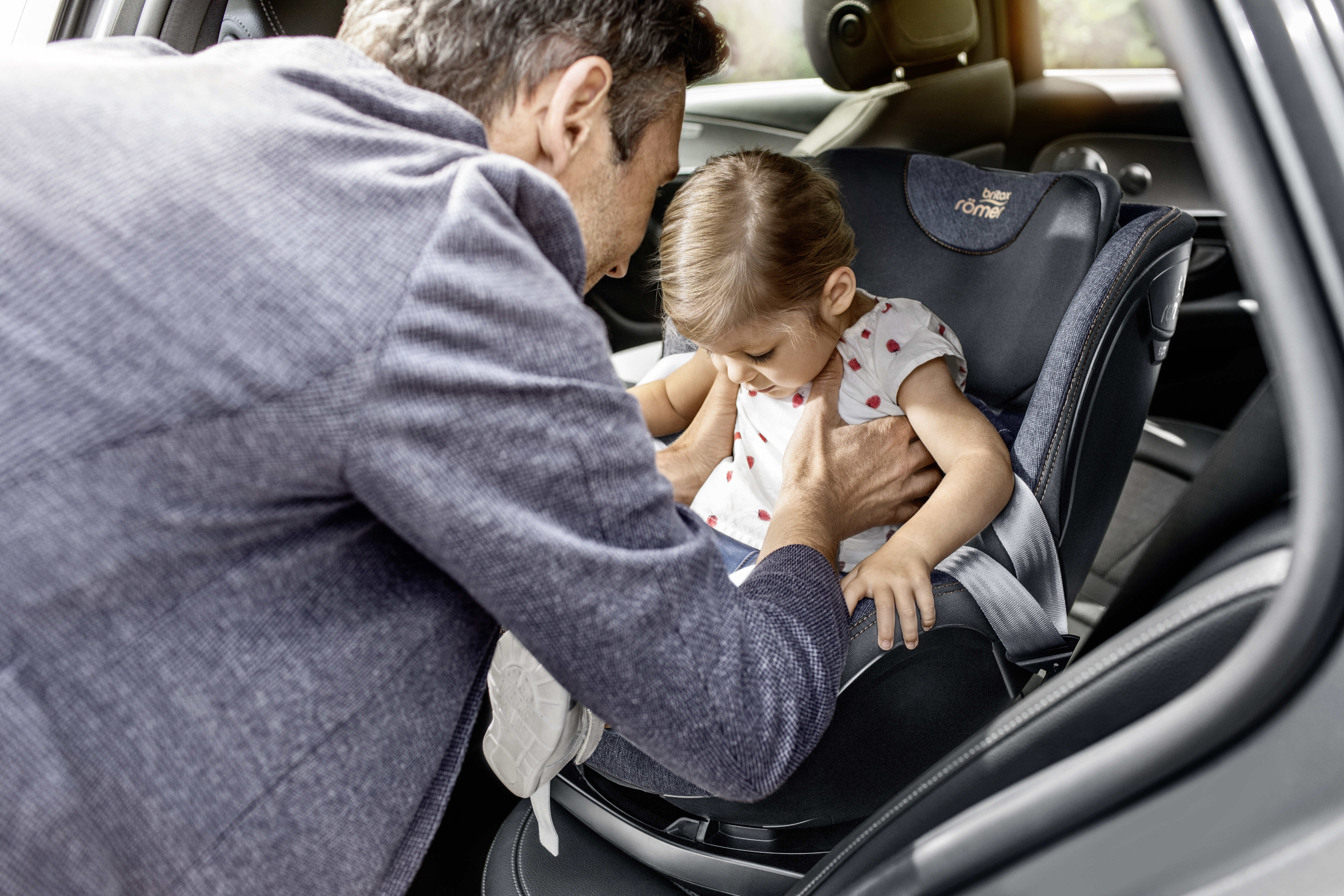 Man strapping his child into a car seat