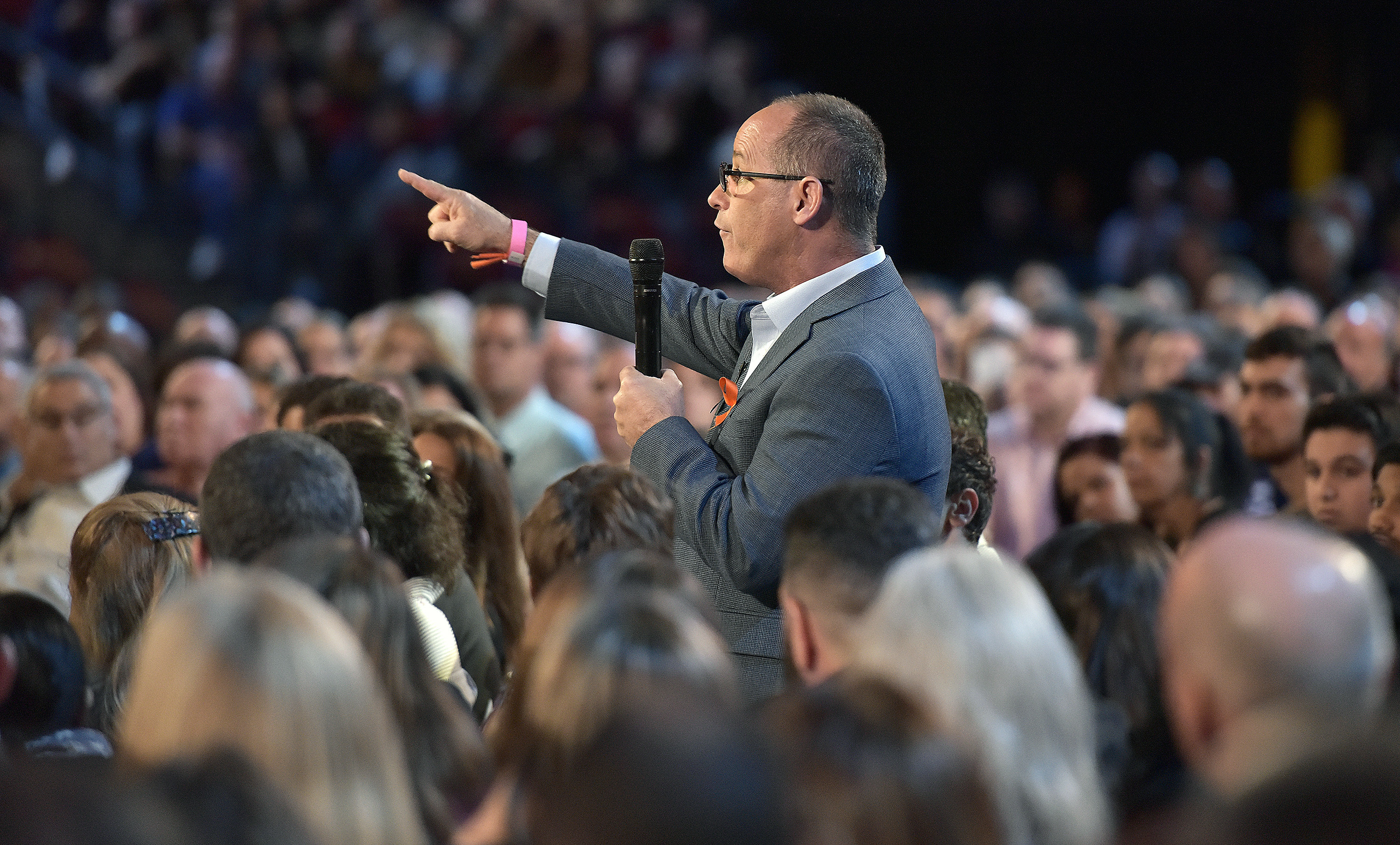 Man in the audience stands up to ask a question in a microphone pointing up to the stage