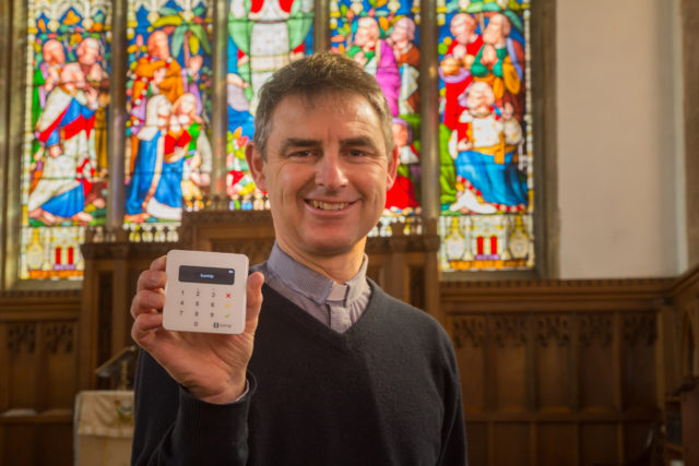 Martyn Taylor, Rector at St George’s Church, Stamford, Lincolnshire, holds a contactless payment device.