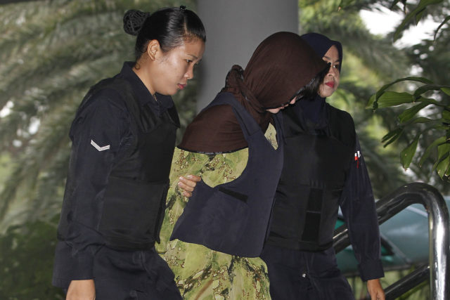 Doan Thi Huong is escorted by police as she arrives for a court hearing at Shah Alam High Court in Malaysia (Sadiq Asyraf/AP)