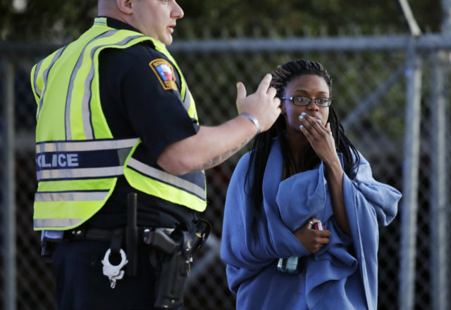 An employee wrapped in a blanket talks to a police officer after she was evacuated at a FedEx distribution centre  (Eric Gay/AP)