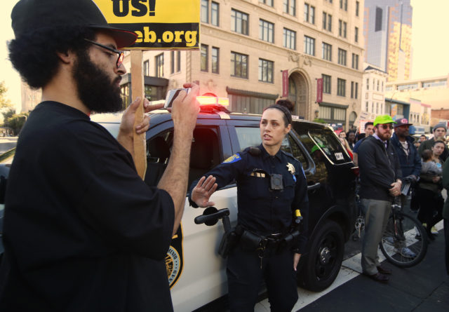 Sacramento police officer J Flure cautions a demonstrator to stay back from her vehicle during a march through Sacramento (Rich Pedroncelli/AP)