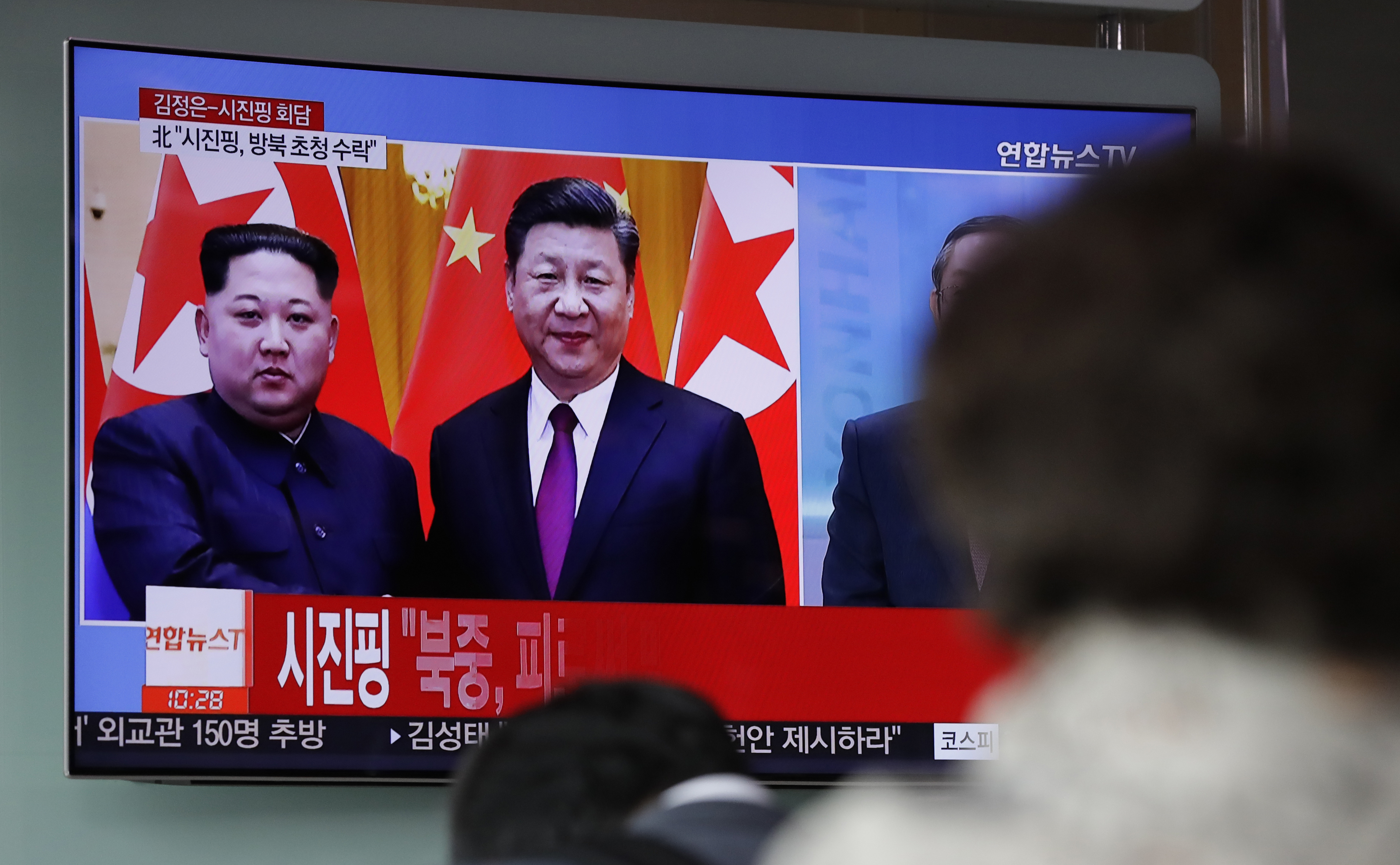 People watch a TV report about the meeting between Kim Jong Un and Xi Jinping (Lee Jin-man/AP)