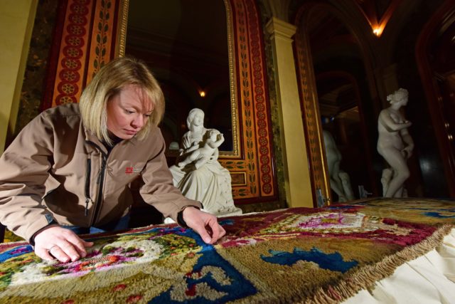 Conservator Caroline Rawson investigates historic clothes moth damage to carpet at Brodsworth Hall in South Yorkshire (English Heritage/PA)