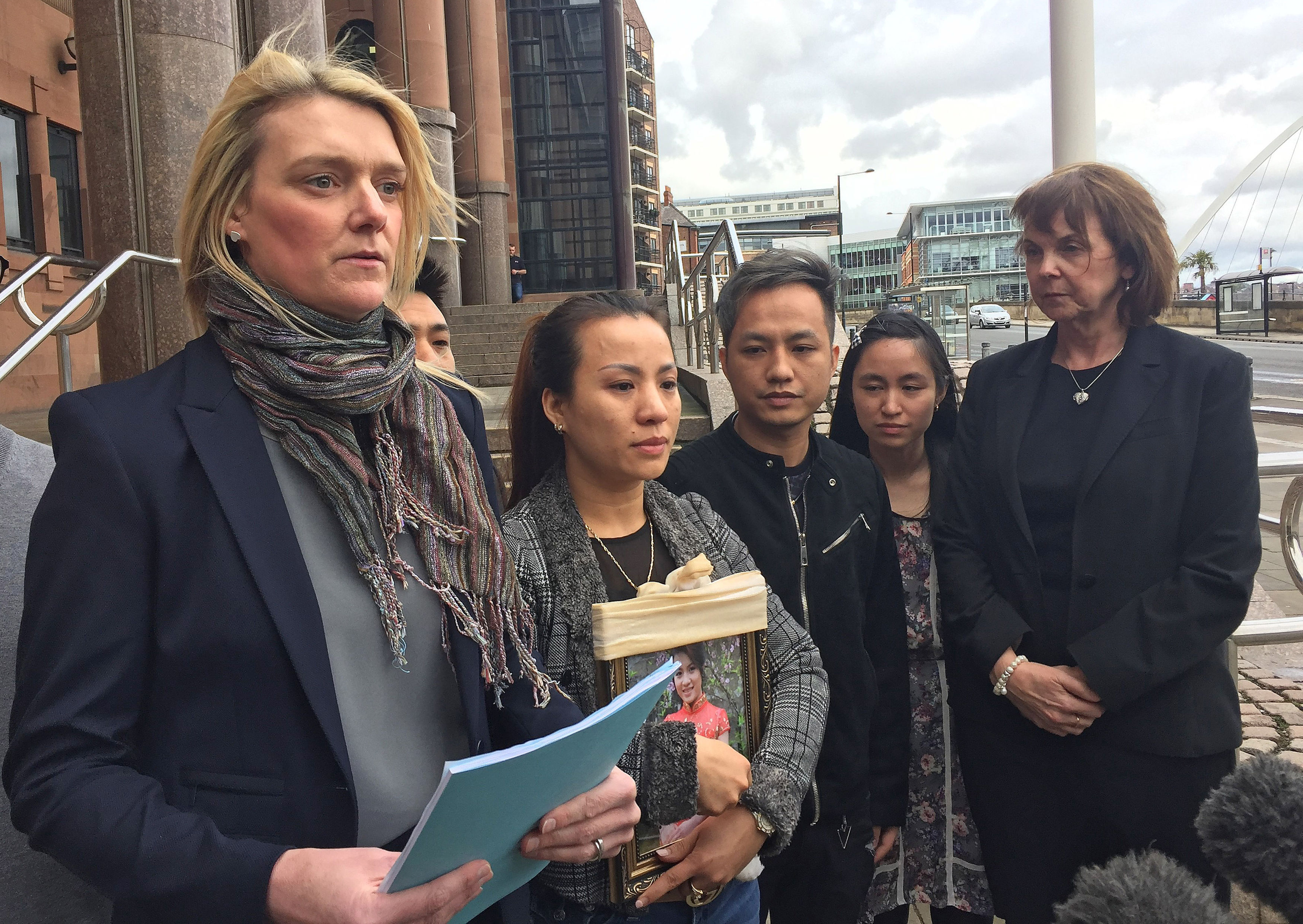 Sergeant Jill Hall reads a statement outside court on behalf of Quyhn Ngoc Nguyen, centre left, holding a picture of her sister Quyen Ngoc Nguyen