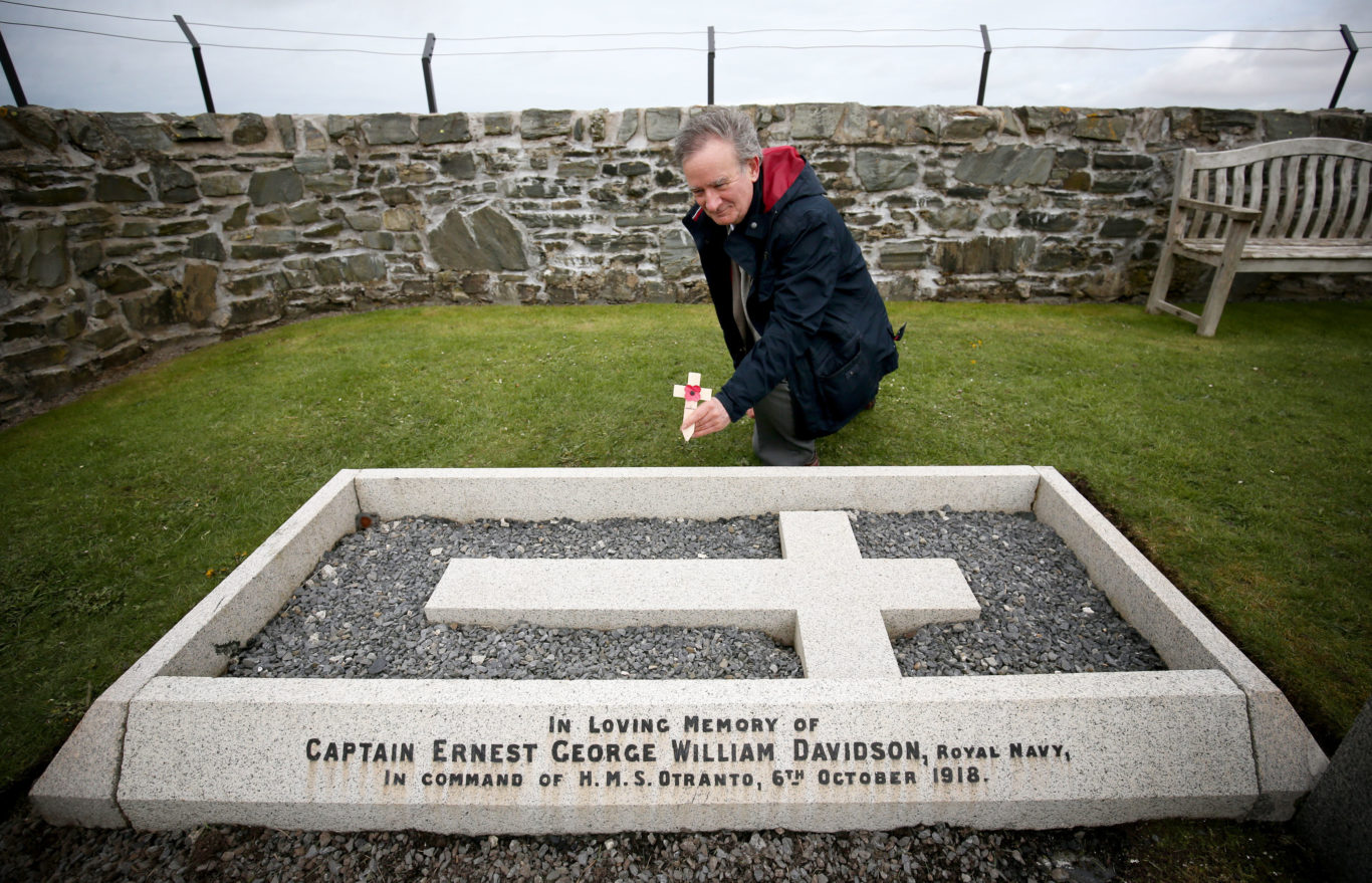 Nick Hide lays a cross at the grave of his grandfather, Captain Ernest Davidson (Jane Barlow/PA)
