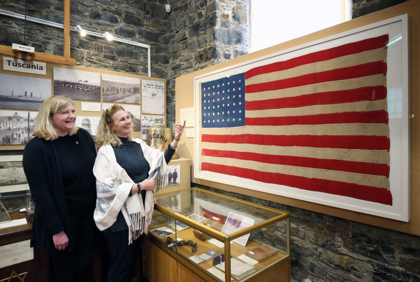 Jenni Minto, from the Museum of Islay Life (left) and Jennifer Jones from the Smithsonian Museum in Washington DC alongside the flag made 100 years ago on the island of Islay for the US crew members who lost their lives in the SS Tuscania disaster (Jane Barlow/PA)