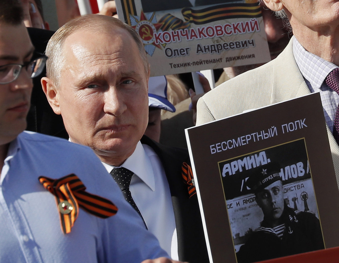 Russian president Vladimir Putin, holds a portrait of his father Vladimir Spiridonovich Putin, as he walks among the crowds (AP)