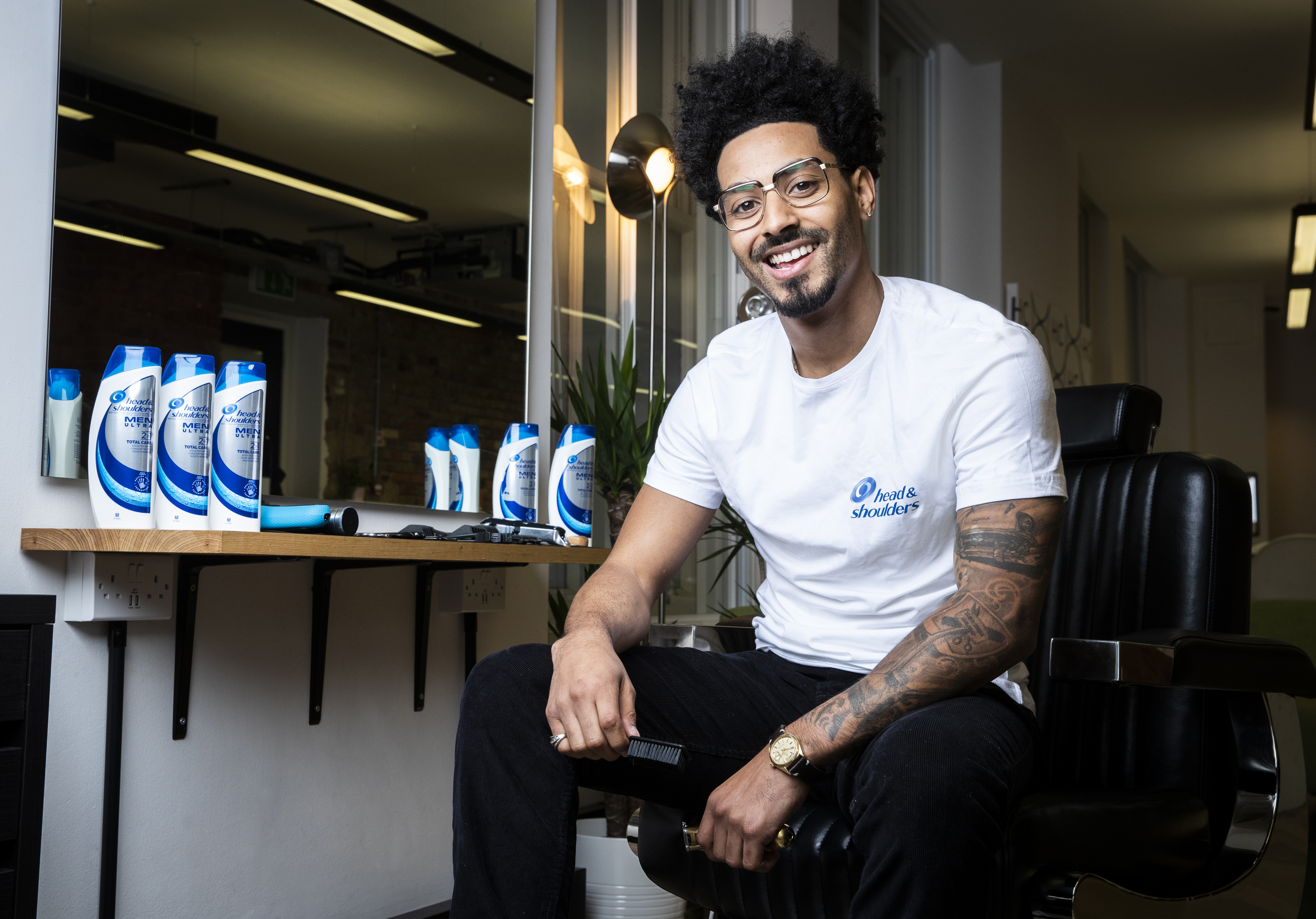 Barber Justin Carr poses in front of some Head & Shoulders bottles