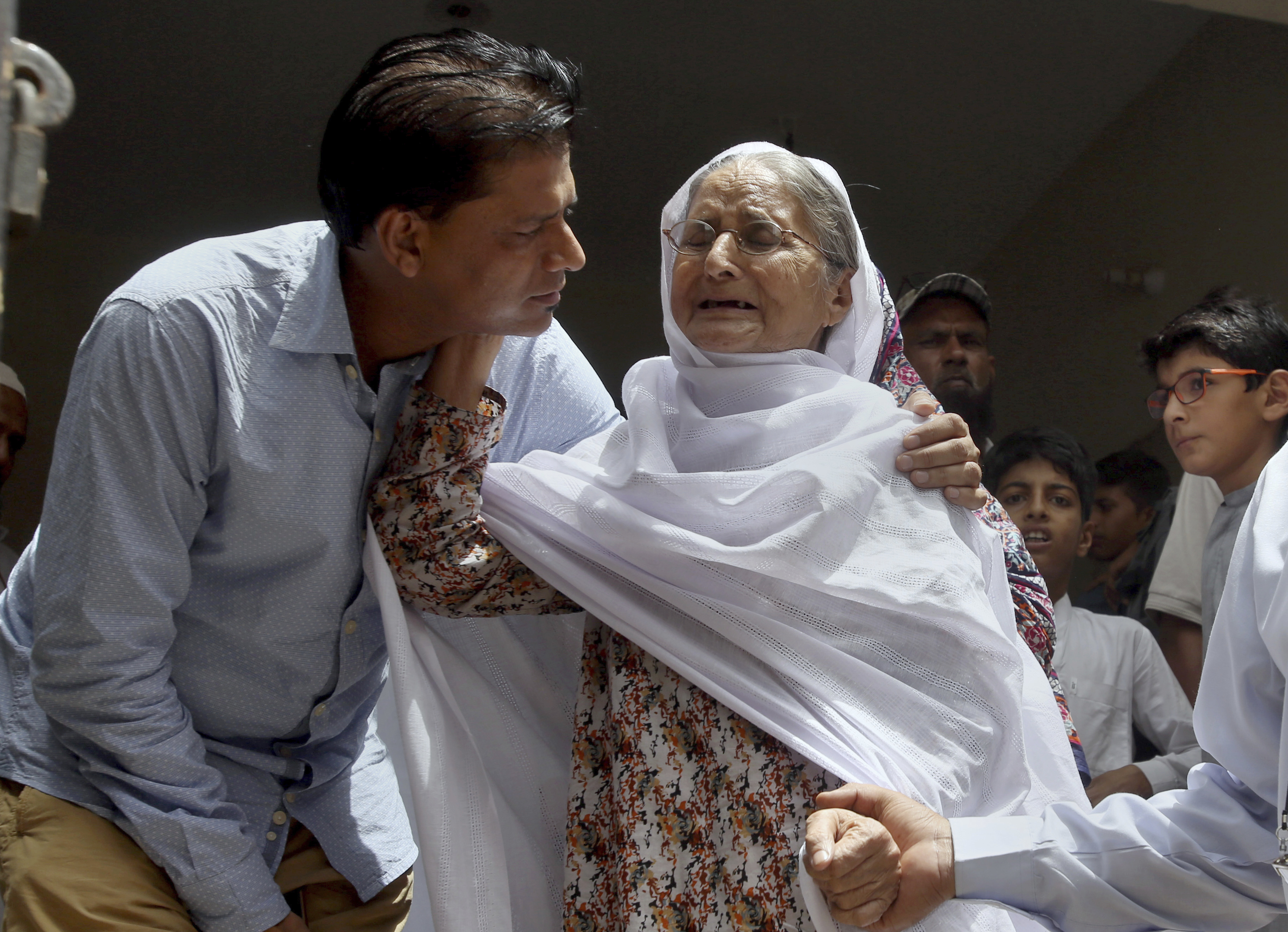 Abdul Aziz Sheikh comforts an elderly woman upon the news his daughter has died in a US school shooting (Fareed Khan/AP)