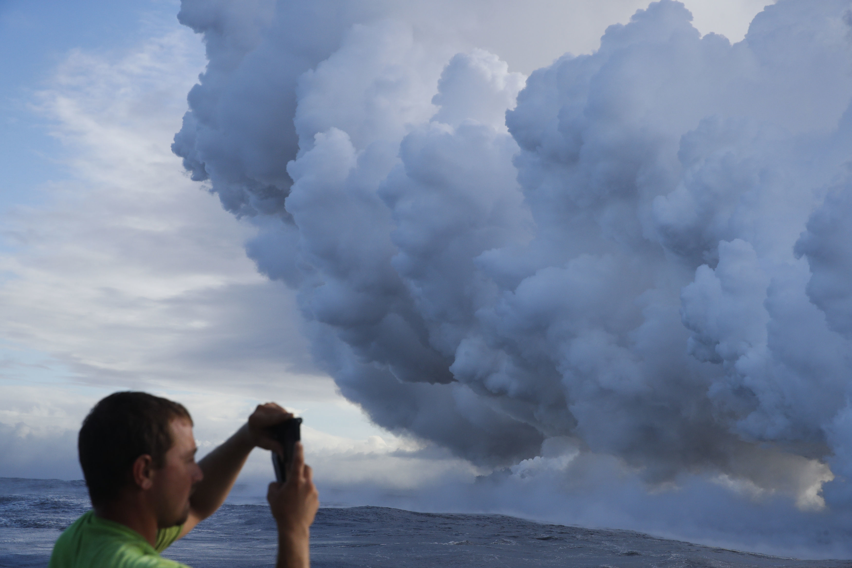 Joe Kekedi takes pictures of a plume of steam as lava enters the ocean near Pahoa (Jae C Hong/AP)