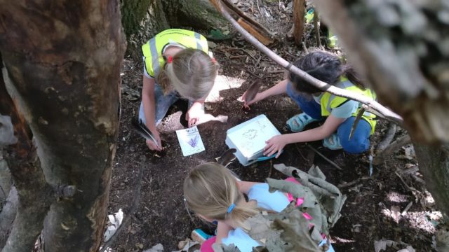 Children writing with berry ink and feather quills