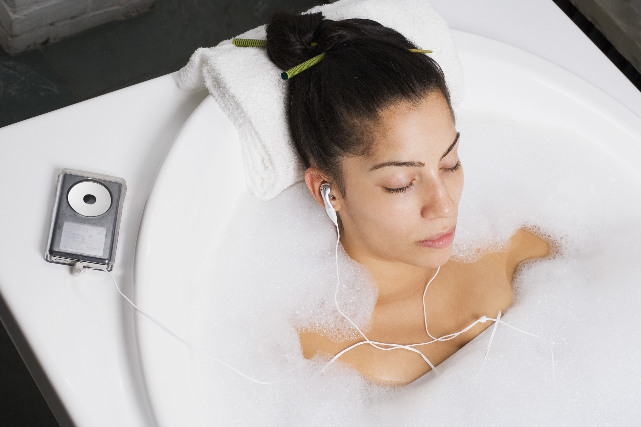 Woman relaxing in bubble bath with music