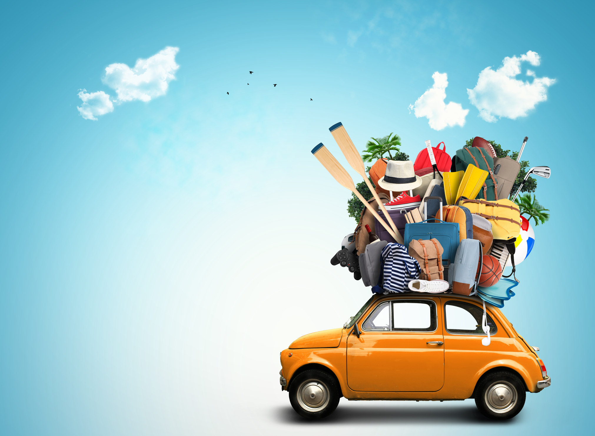 Generic stock image of a car comically loaded with luggage and holiday gear on the roof