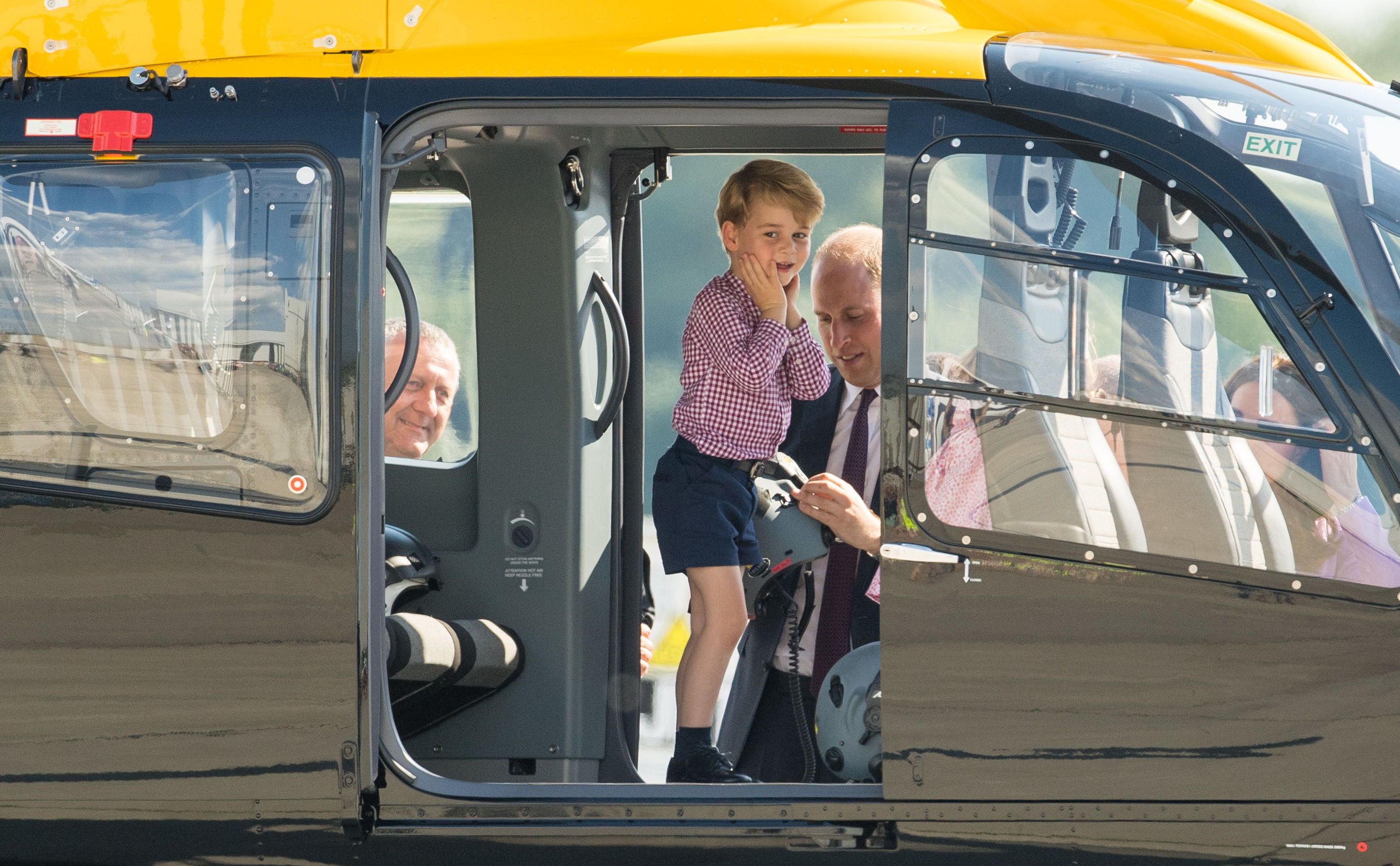 Prince George stands in a rescue helicopter as his father the Duke of Cambridge adjusts a helmet for him to wear, during a visit to Airbus in Hamburg, Germany with the Duchess of Cambridge and sister Princess Charlotte 