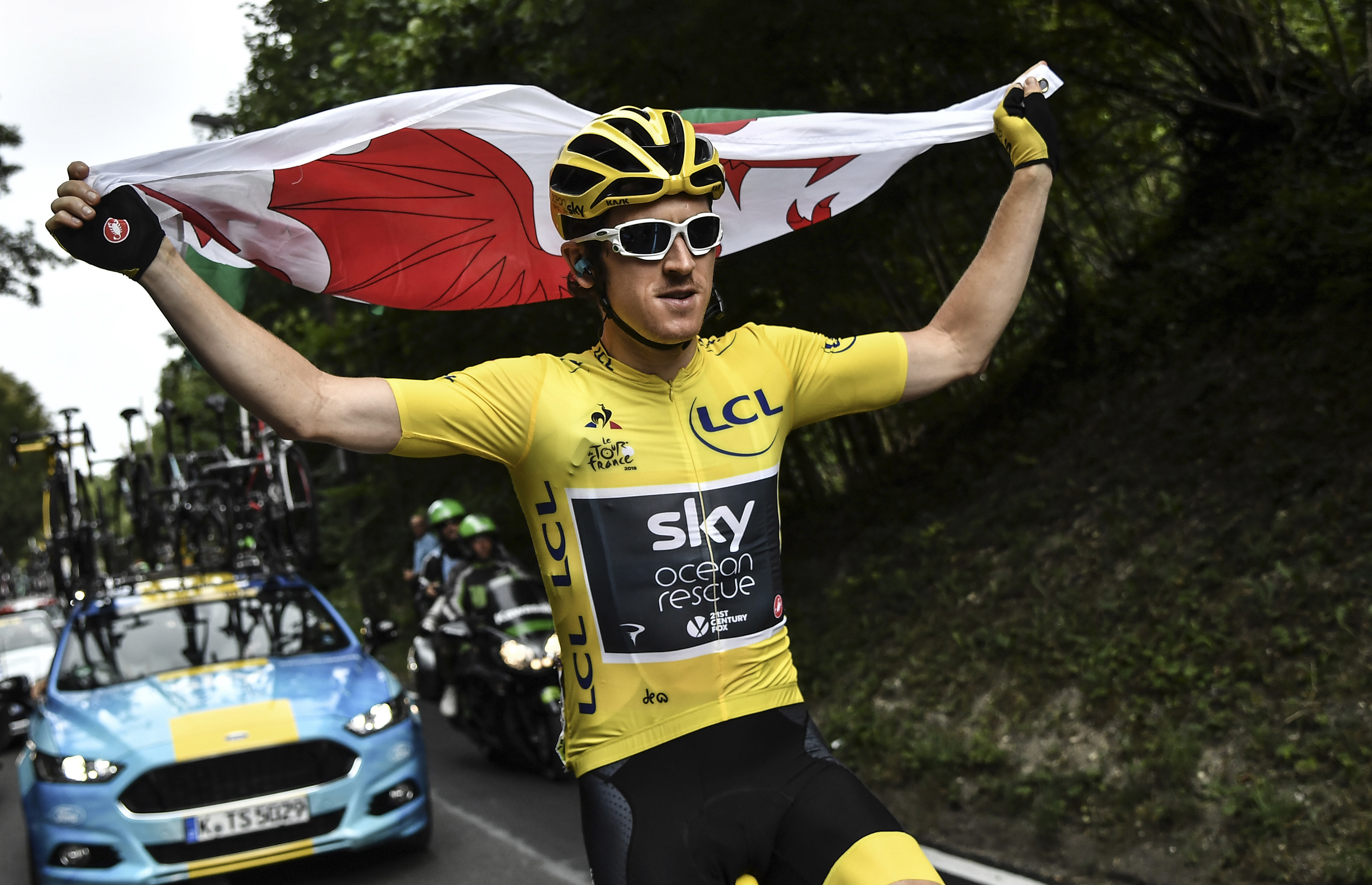 Britain's Geraint Thomas, wearing the overall leader's yellow jersey, holds the flag of Wales during the 21st and last stage of the 105th edition of the Tour de France cycling race between Houilles and Paris Champs-Elysees,