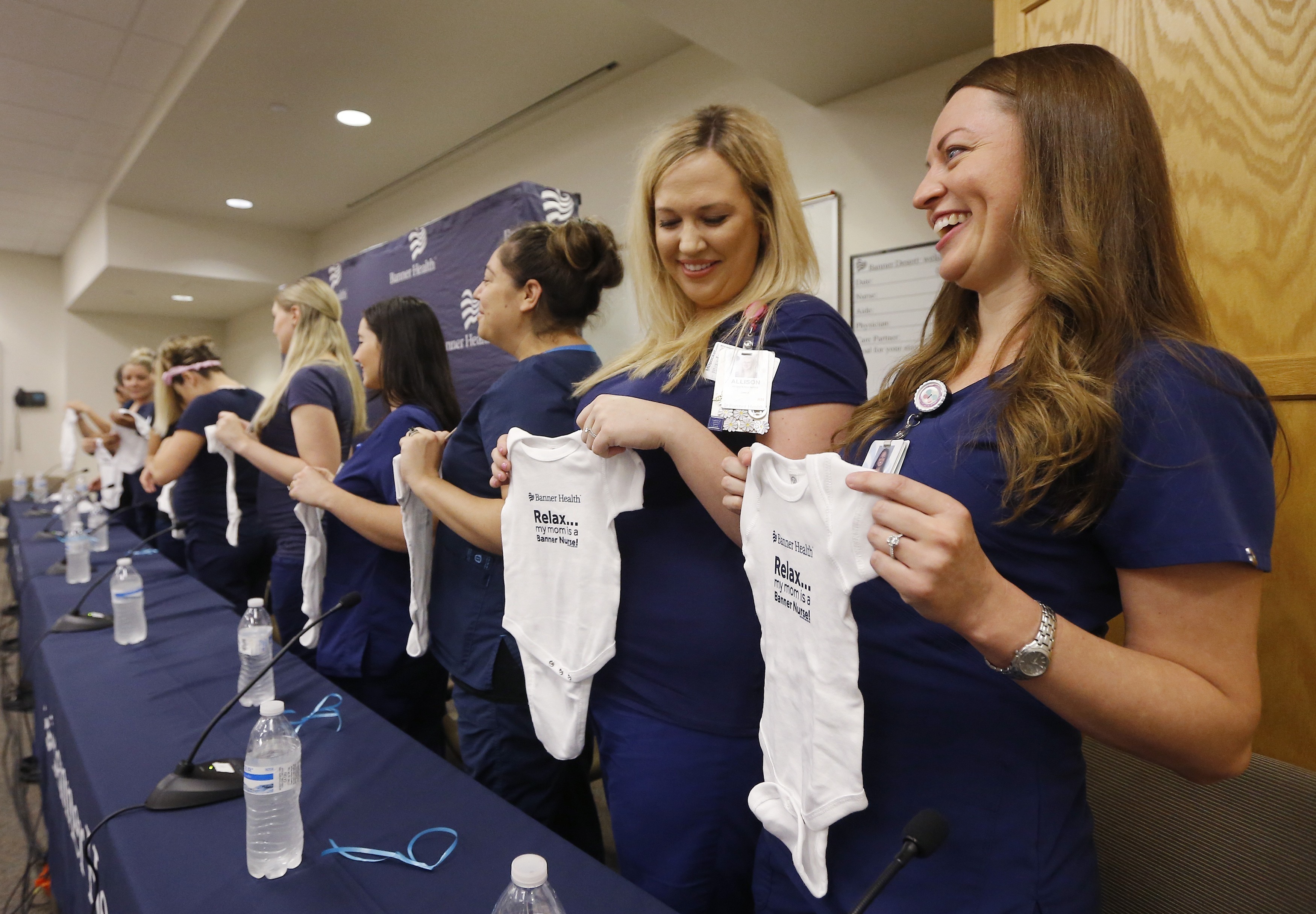 Pregnant nurses hold up baby outfits in Mesa, Arizona 