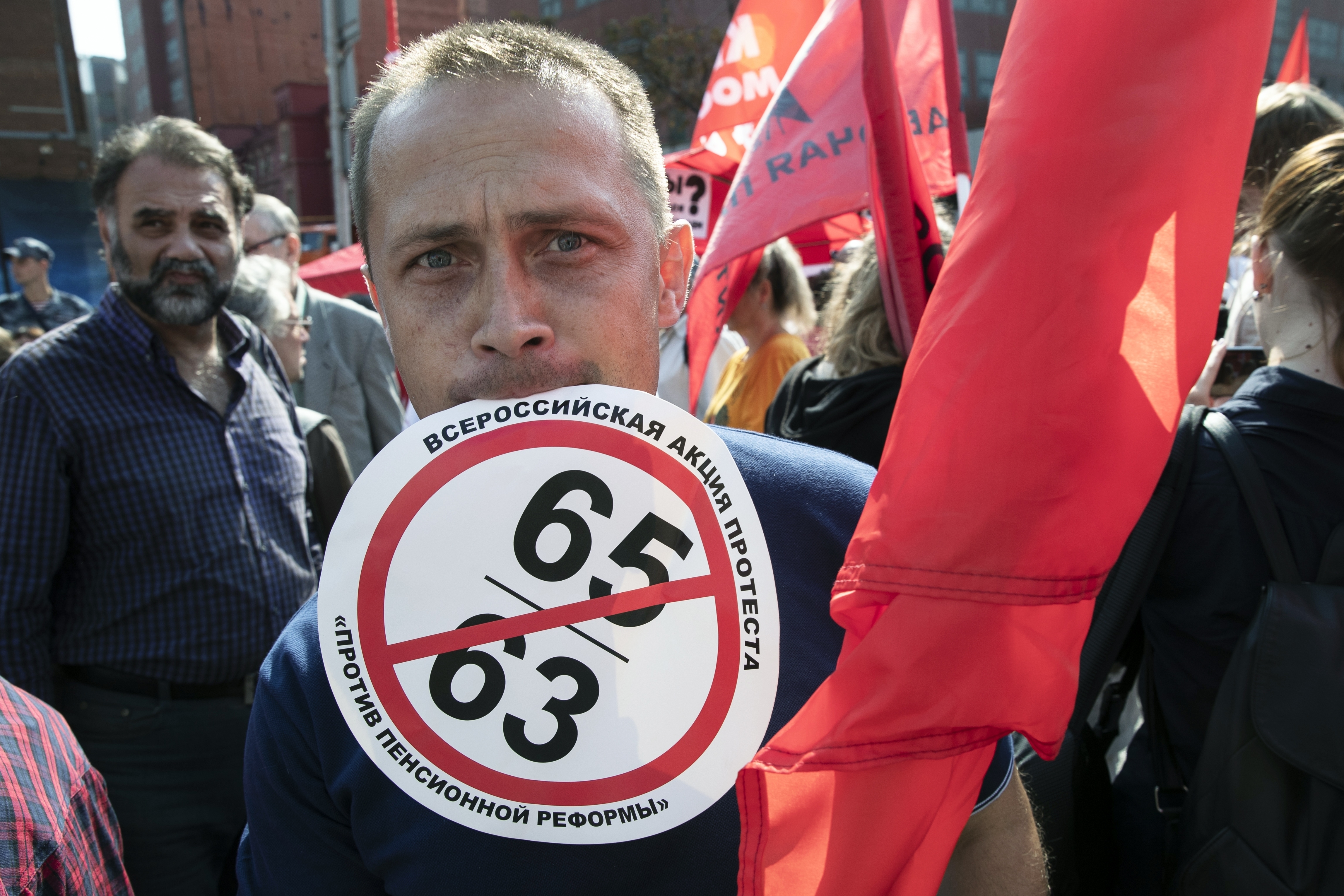 A man holds in his mouth a banner reading "An all-Russian protest against pension reform" during the Communist Party rally in Moscow
