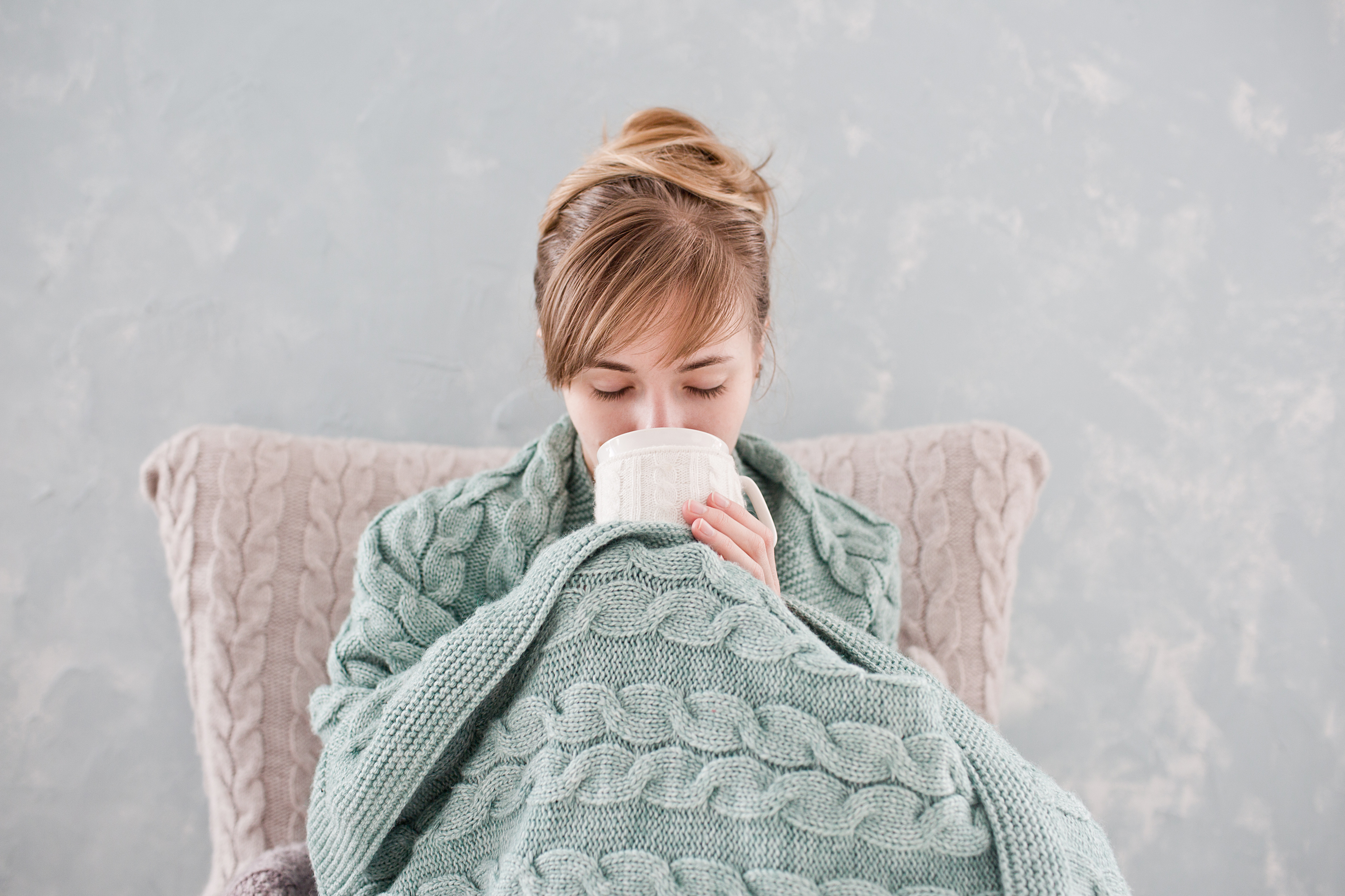 Woman wrapped in blankets with hot chocolate