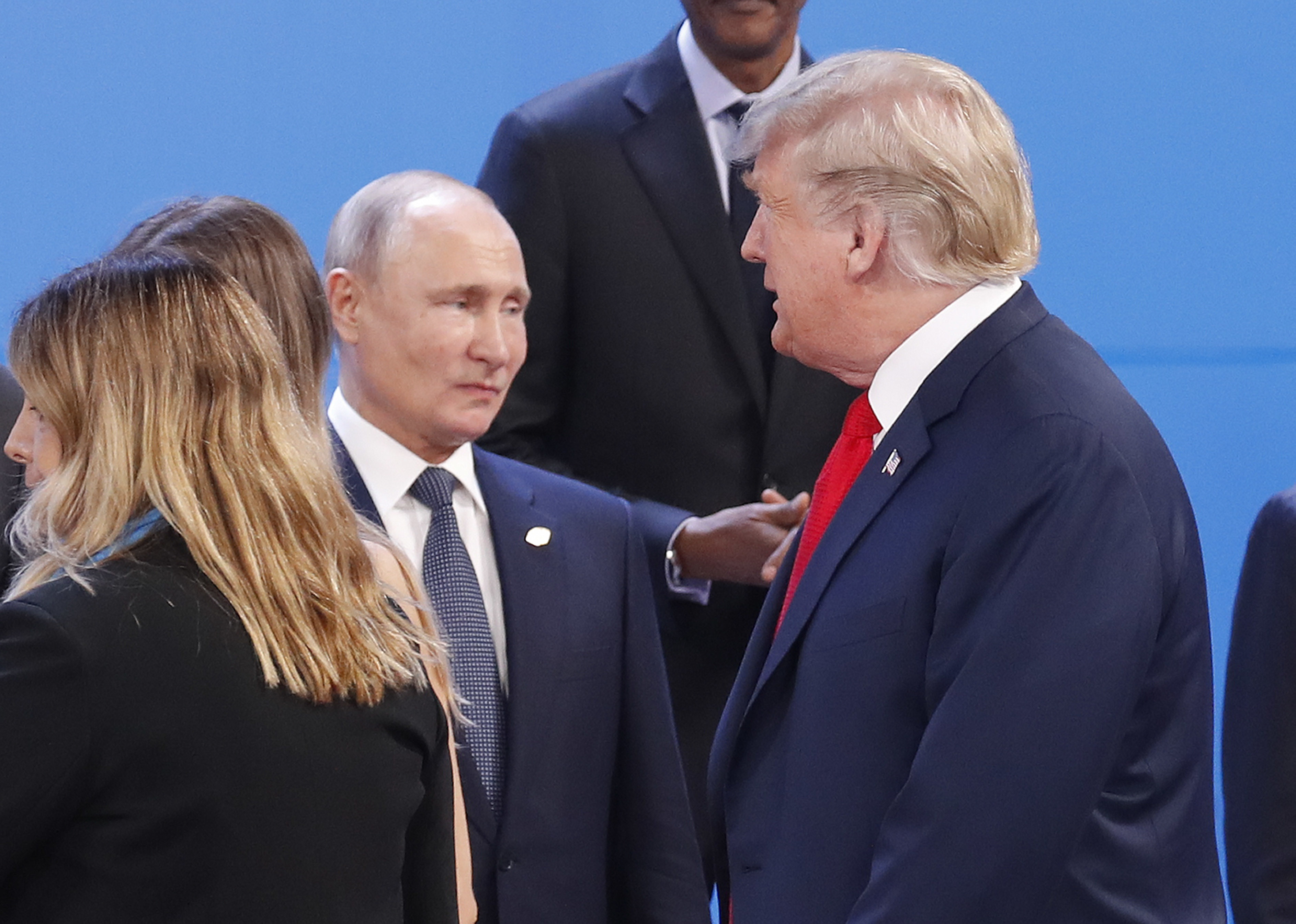 Donald Trump walks past Vladimir Putin as they gather for the group photo at the start of the G20 summit in Buenos Aires