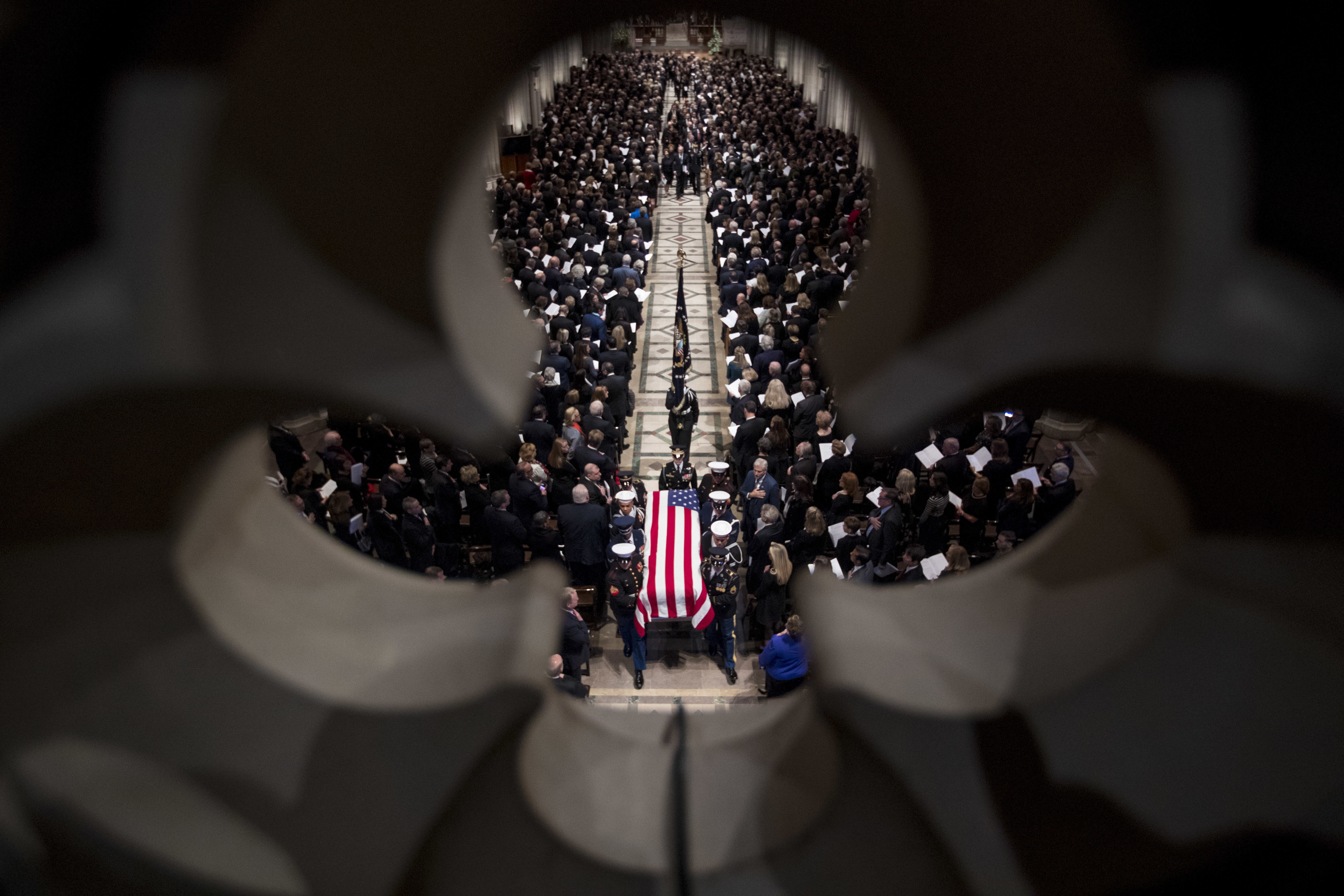The flag-draped coffin of former president George HW Bush is carried out by a military honour guard