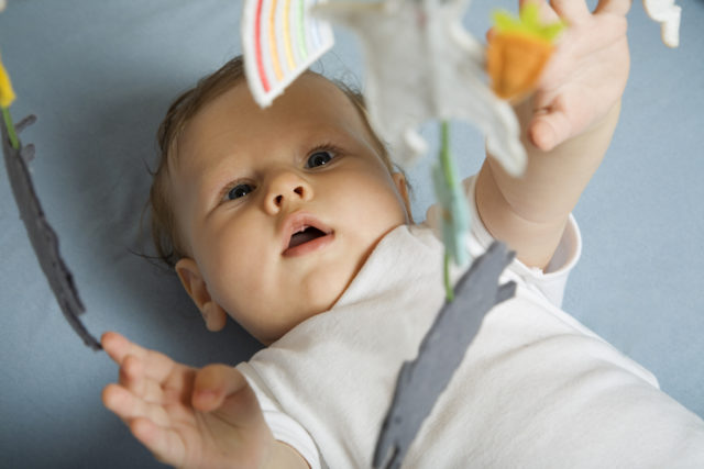 A baby playing in its cot