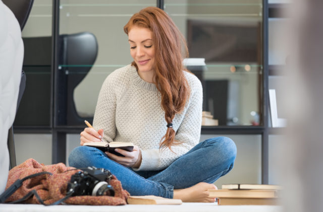 Generic photo of woman sat on the floor writing in a diary