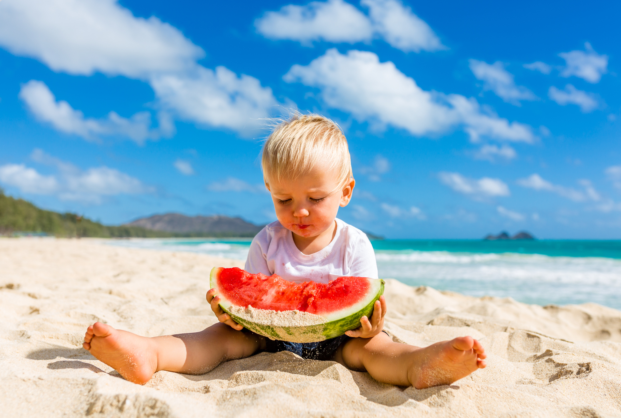 Cute Toddler Enjoys Big Slice of Watermelon on Beach