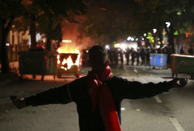 A protester holds stones as police block a road during clashes in Tirana