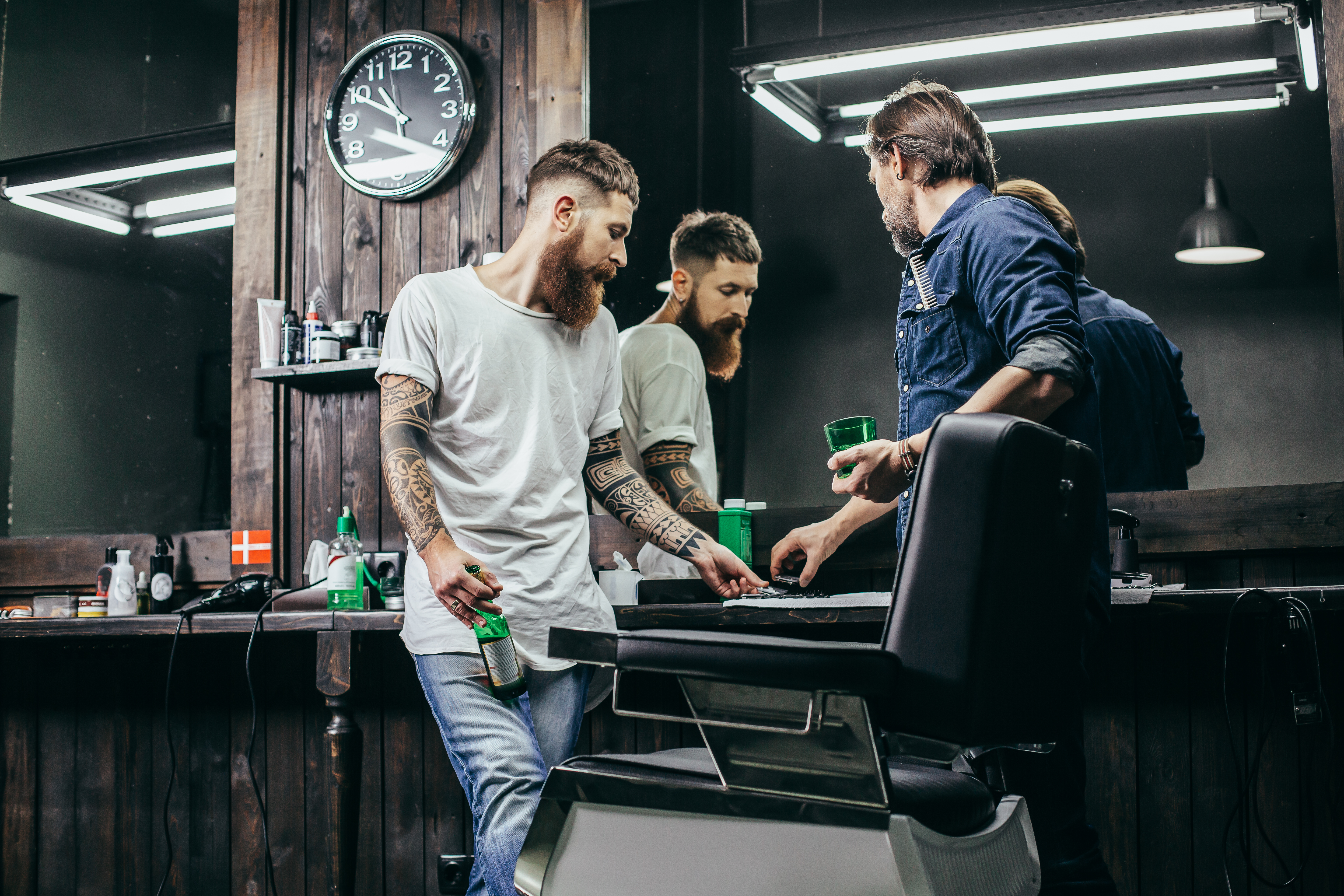 Two men looking at hair clipper blades while being in barbershop