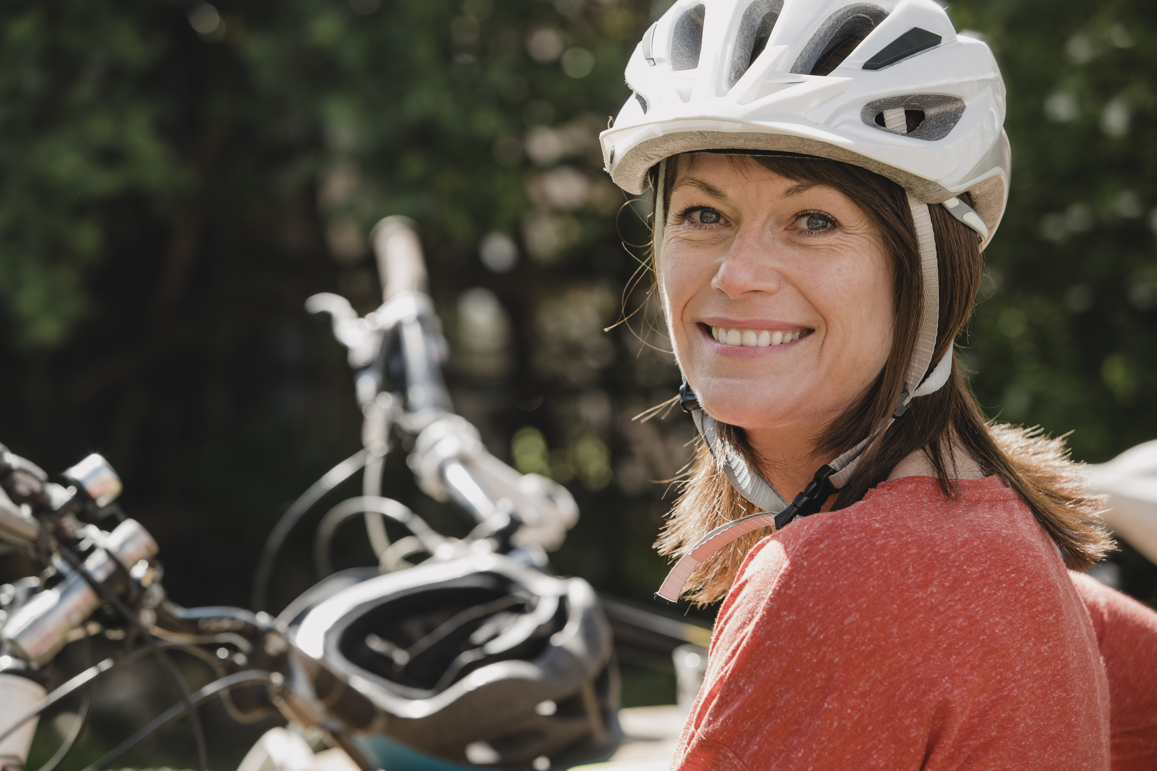 Headshot of a mature female wearing a cycling helmet and looking at the camera and smiling.