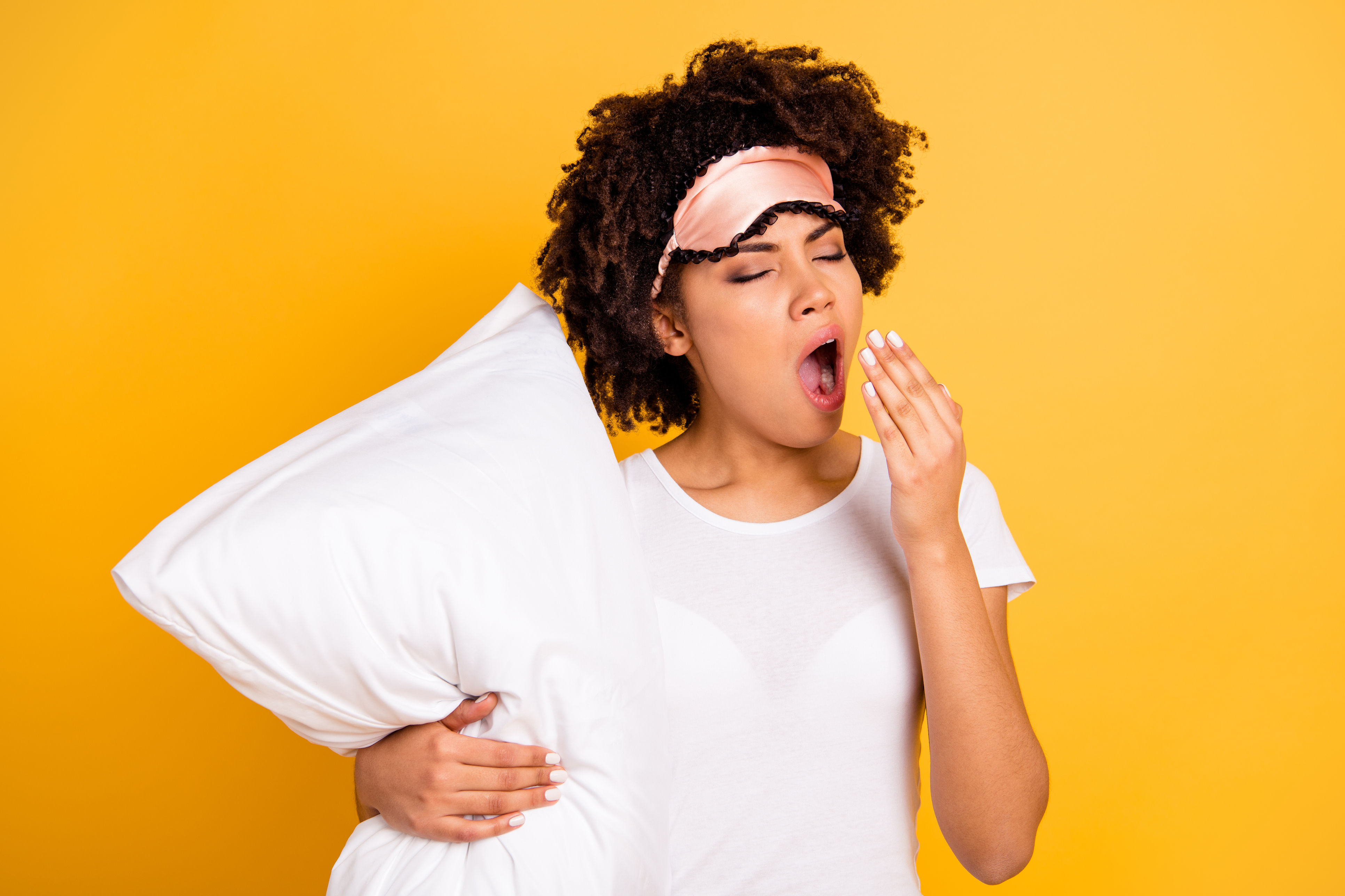 Close up photo beautiful amazing she her dark skin lady hand yawn hug embrace pillow awakening hard early wear sleep mask casual white t-shirt isolated yellow bright vibrant vivid background.