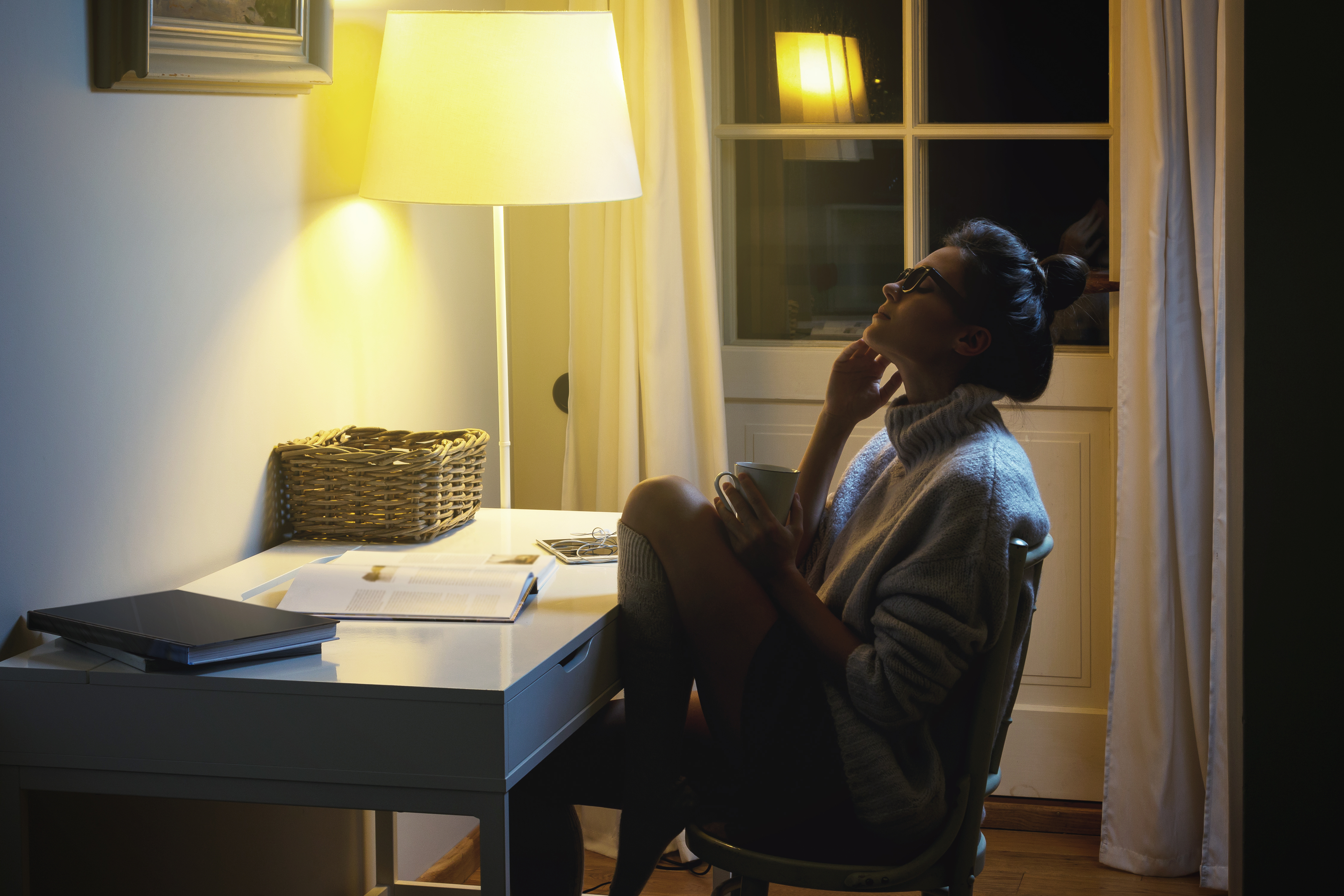 Woman wearing a warm woolen sweater is reading book at middle of the night