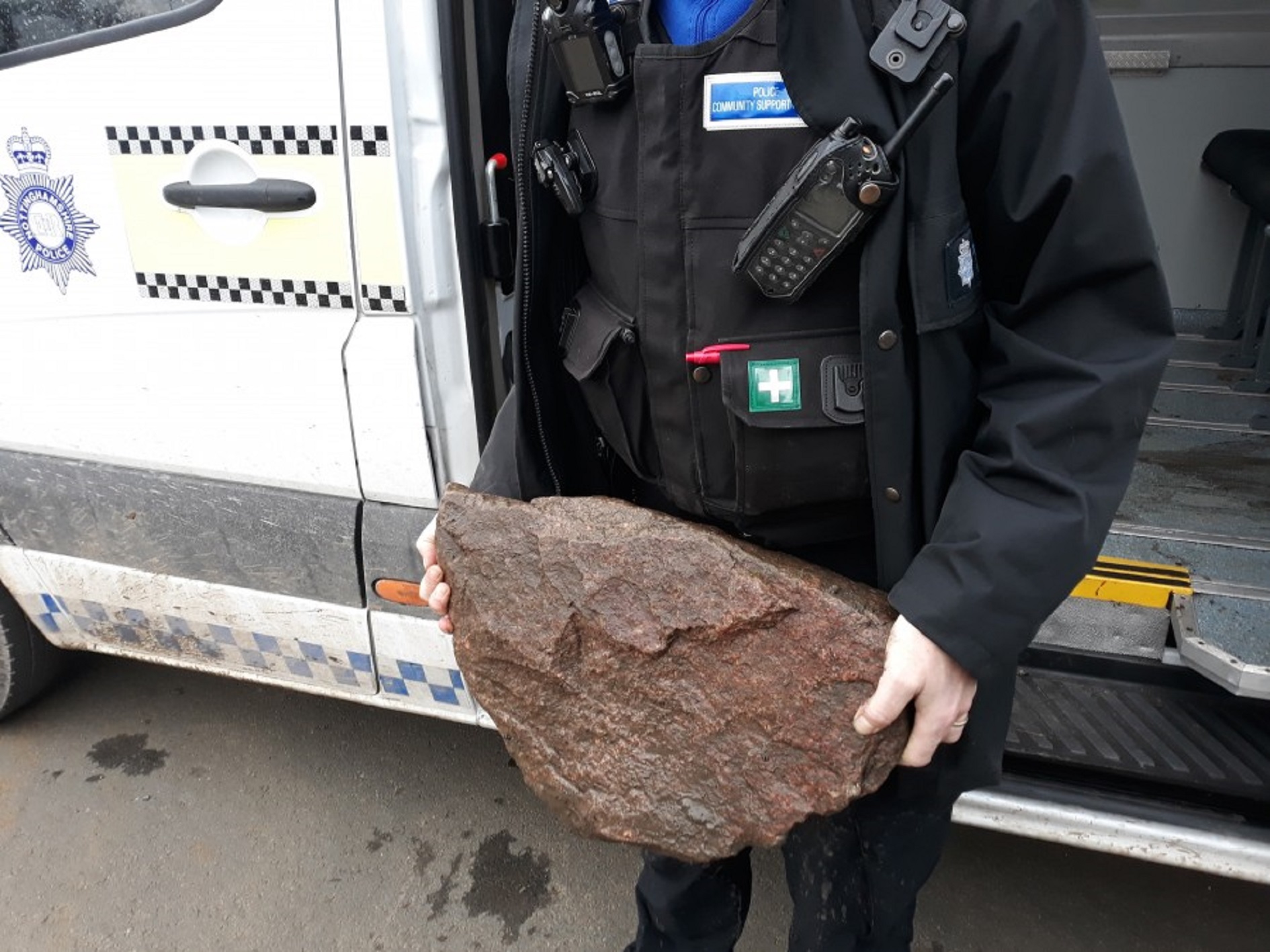 A police officer stands with a rock