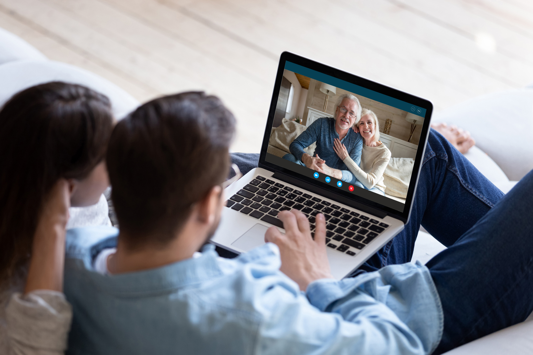 Couple communicating with elderly parents living abroad using computer and videocall application, laptop screen view over spouse shoulder. Distant virtual communication modern technology usage concept