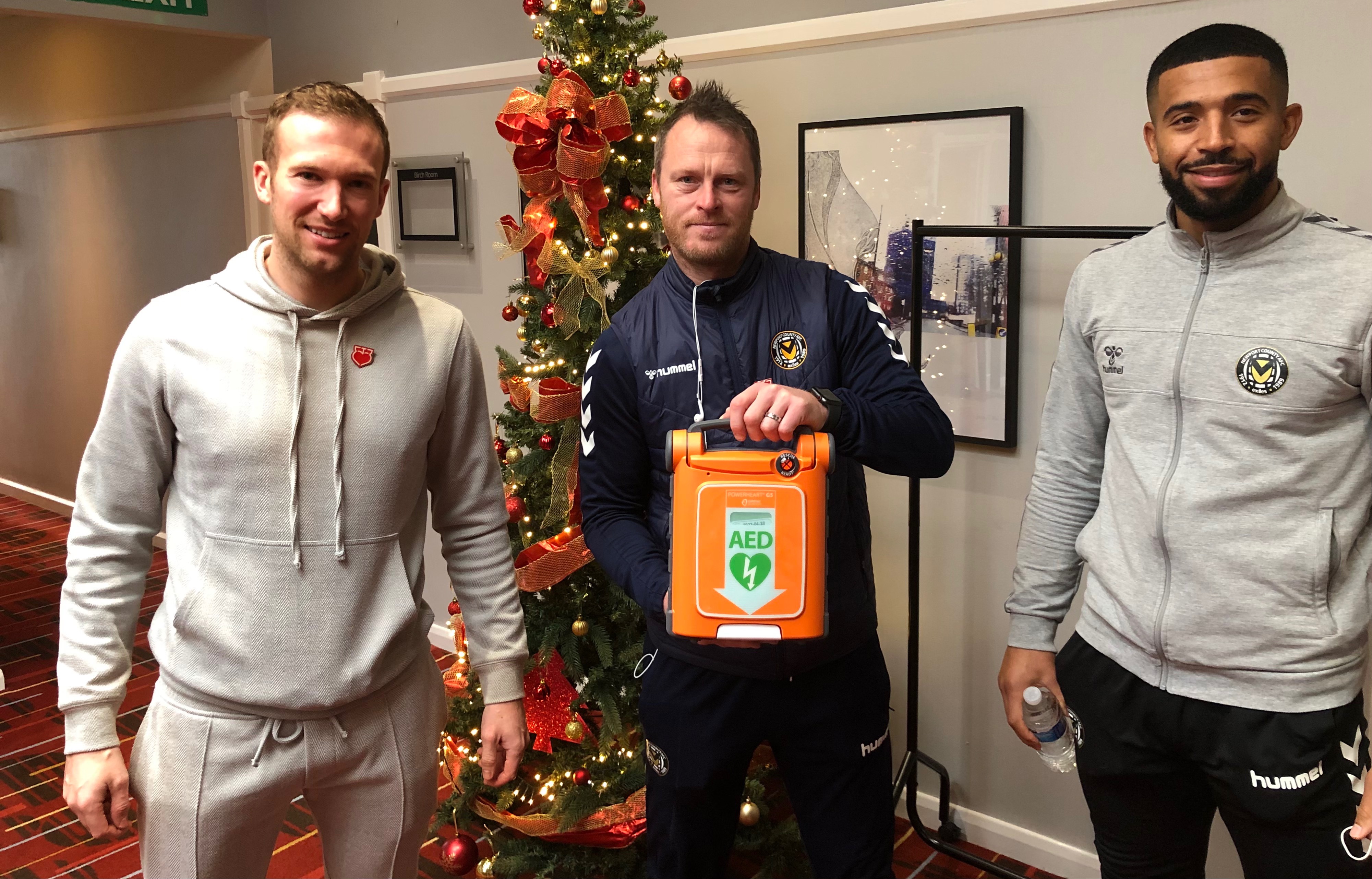 Charlie Edinburgh recently presented Newport manager Michael Flynn and captain Joss Labadie with an automated external defibrillator on behalf of the Justin Edinburgh 3 Foundation