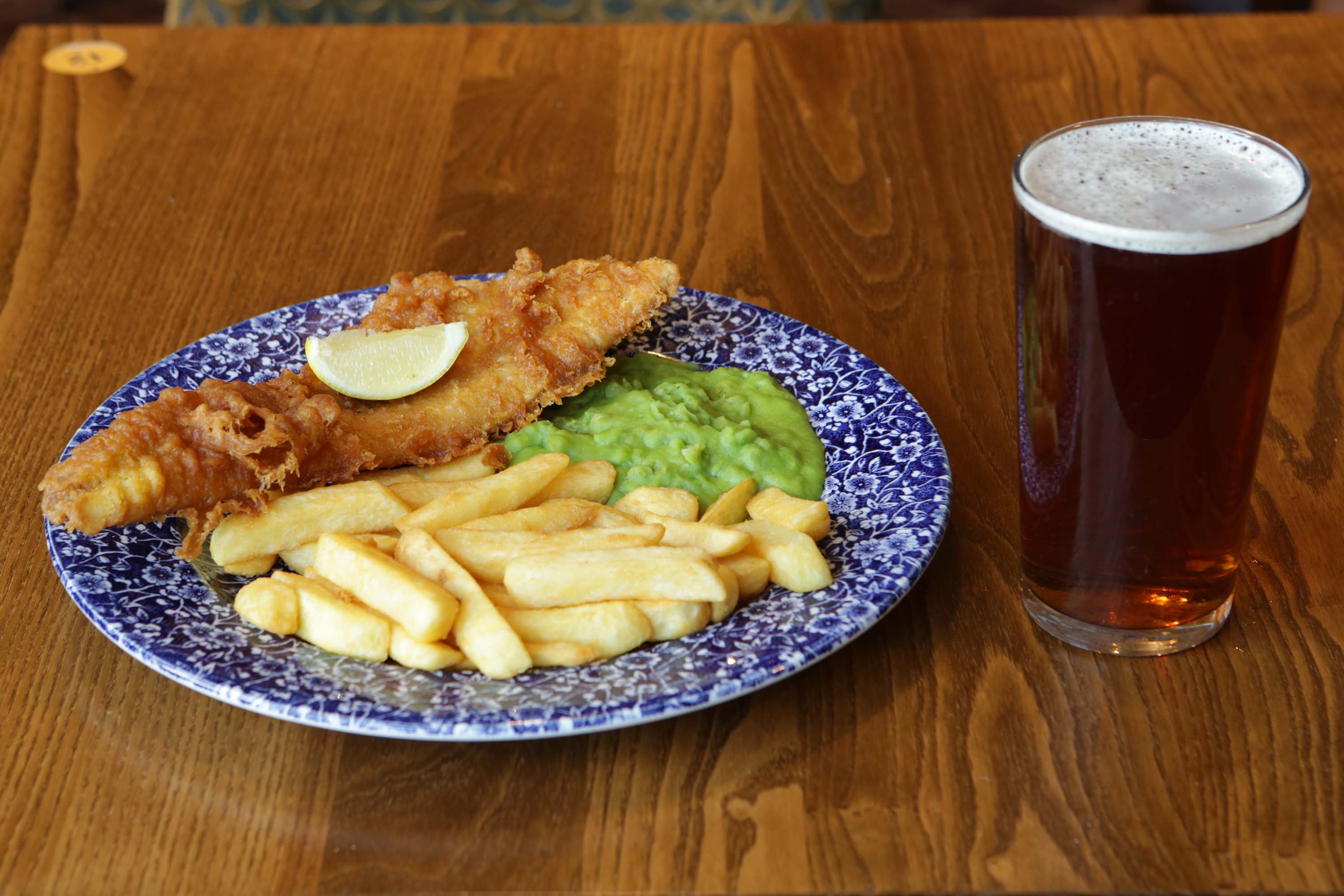 A plate of fish and chips alongside a pint of beer