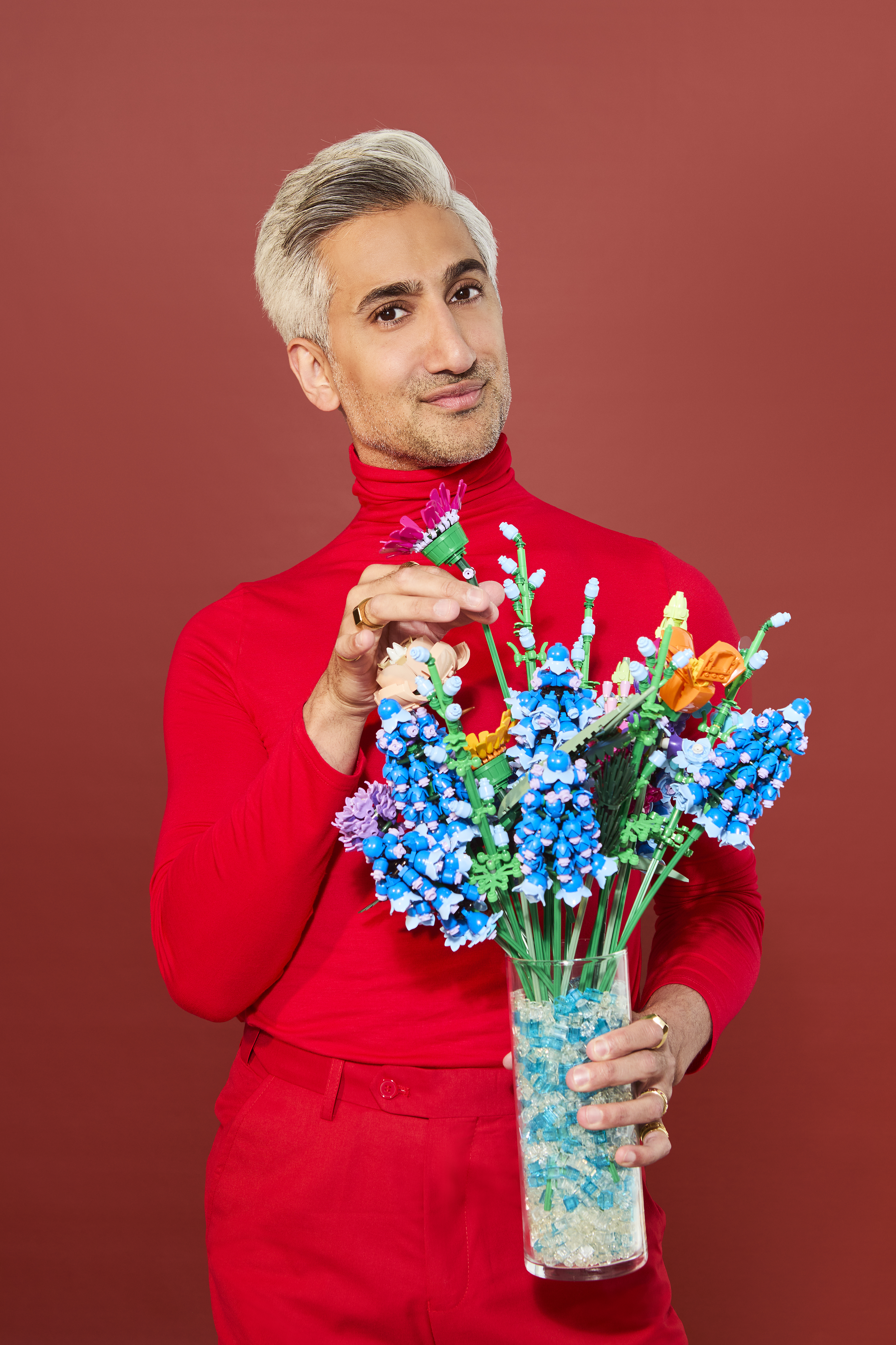 Tan France holding a vase of faux flowers